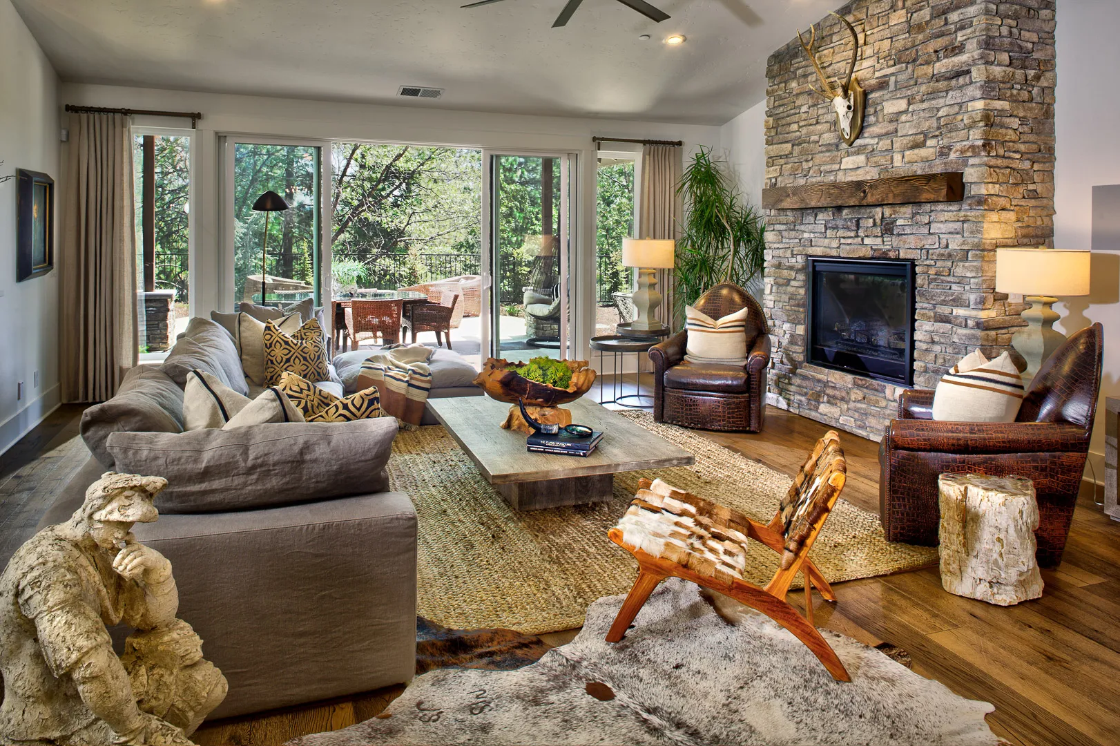 Great room with floor-to-ceiling stacked stone fireplace, timber mantel, and sliding doors to the patio
