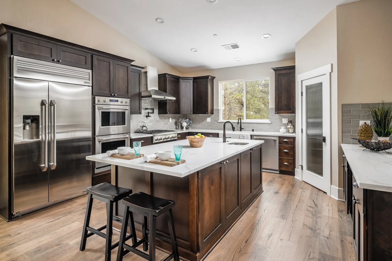 Kitchen with espresso cabinetry, white quartz island, stainless appliances, and saddle bar stools