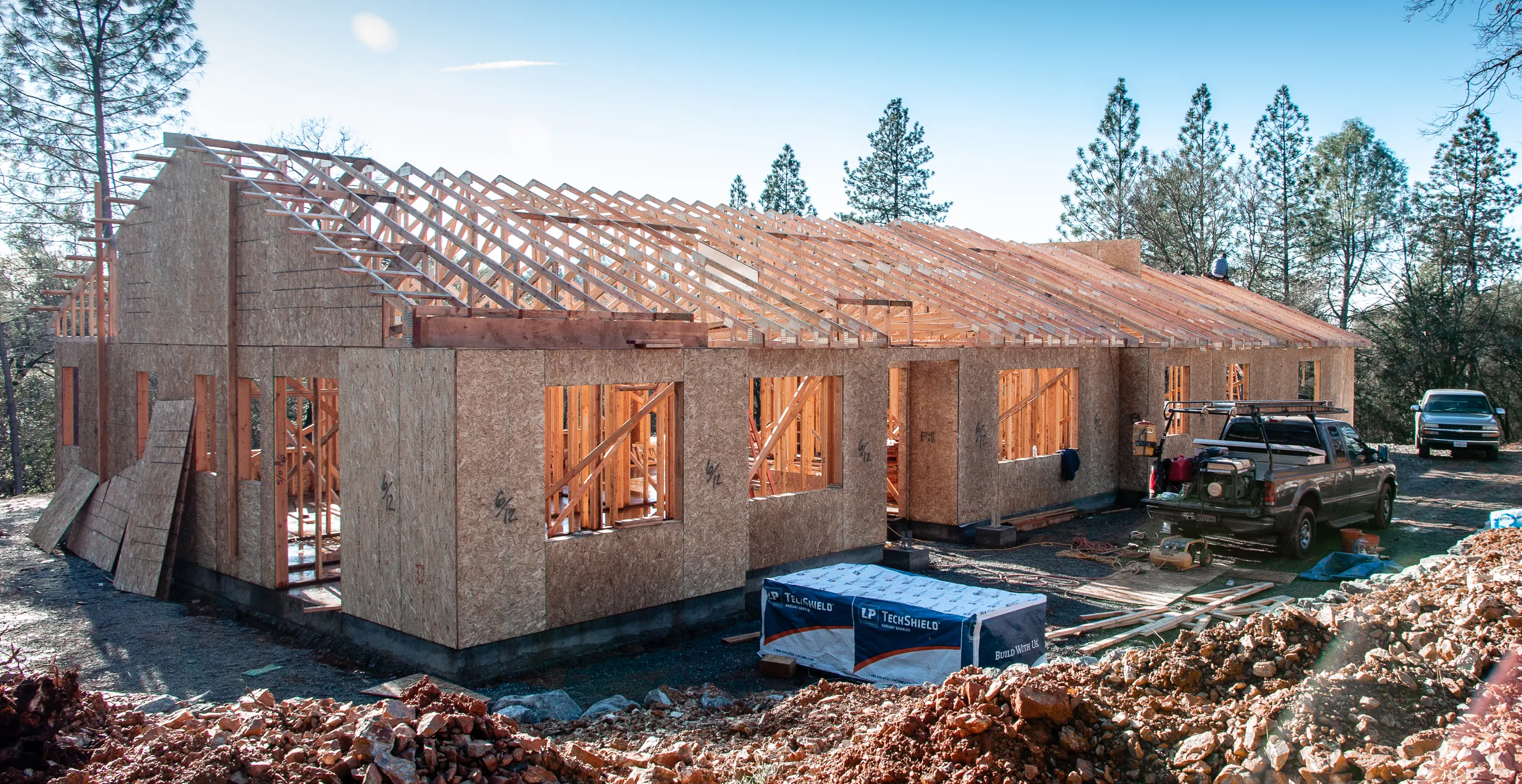 A Sherman custom home under construction — roof framing and structural sheathing in the foothills