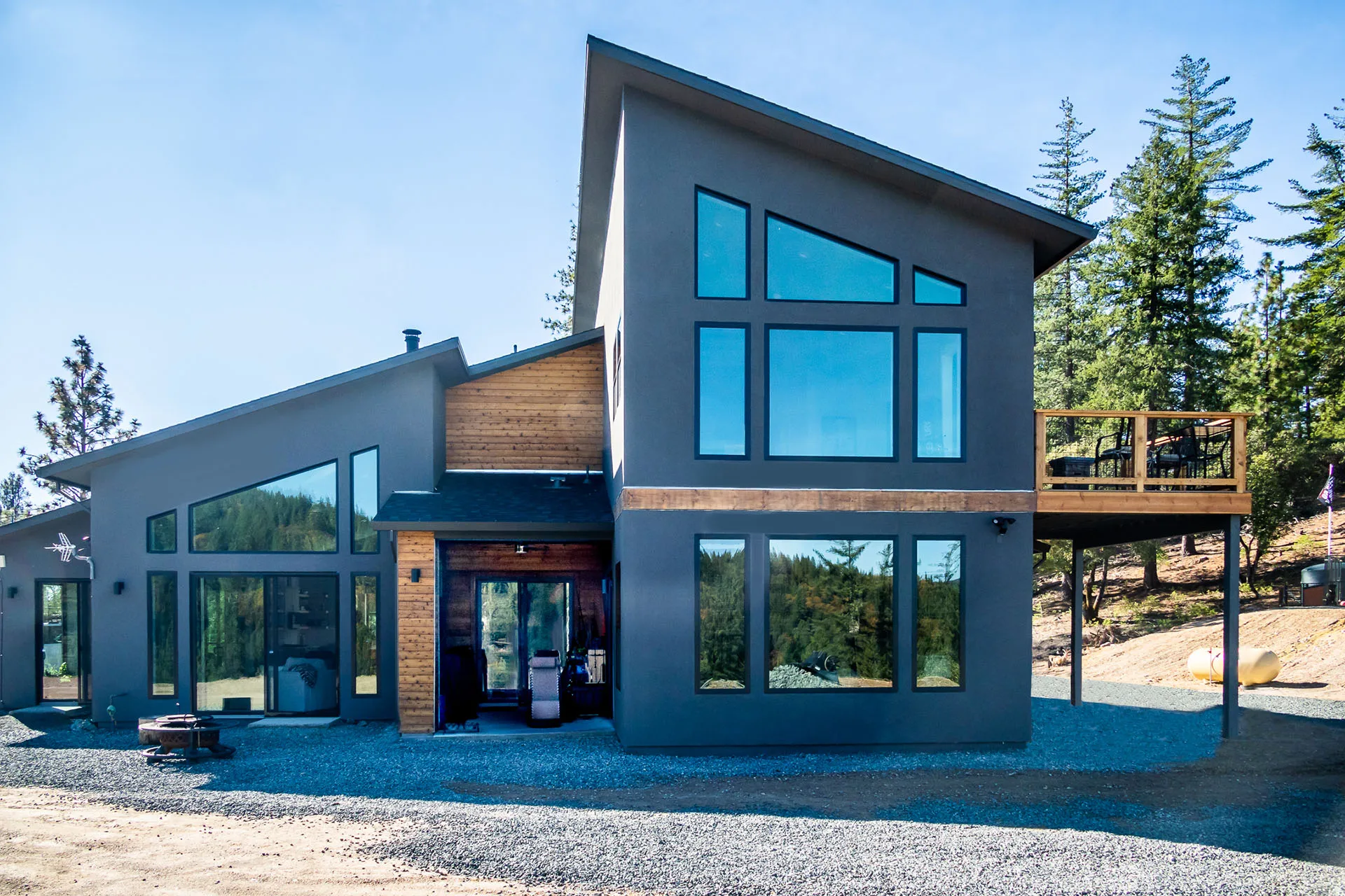 Rear view of the Colfax cabin's shed rooflines, tall window walls, and elevated wood deck