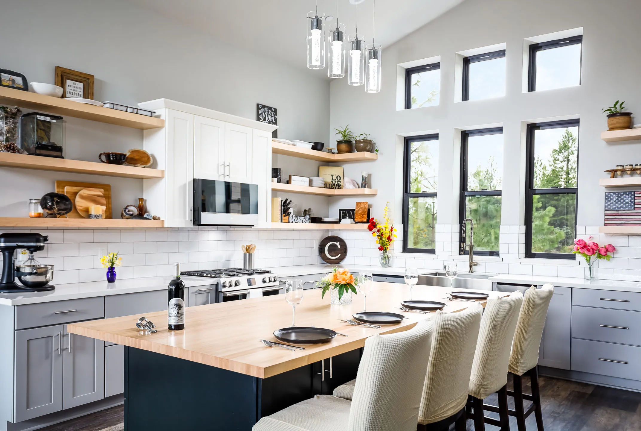 Vaulted cabin kitchen with maple open shelving, white subway tile, and butcher-block island seating