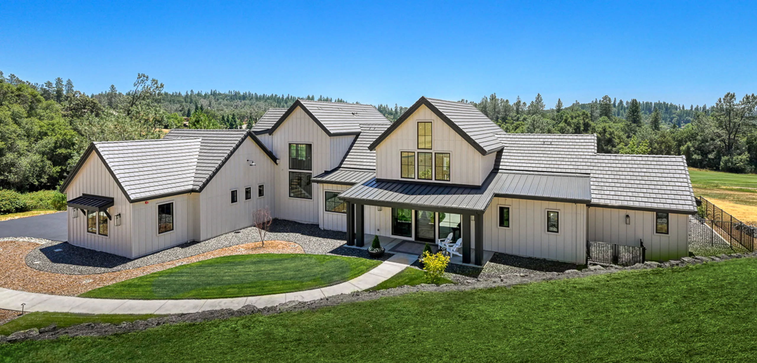 Aerial view of a modern farmhouse custom home with lawn in Meadow Vista, California
