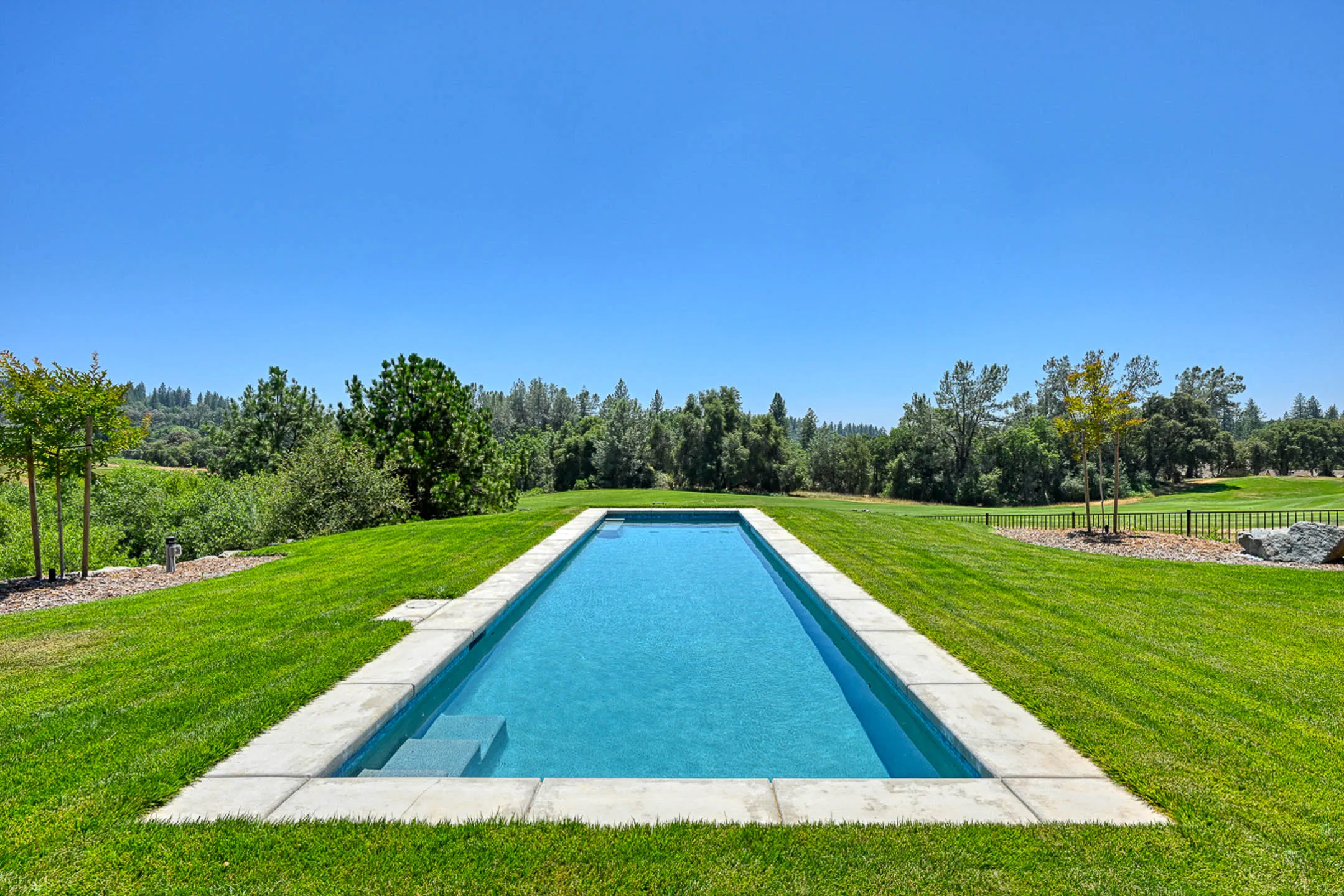 Concrete-edged lap pool set into the lawn with golf course views at a Sherman custom home