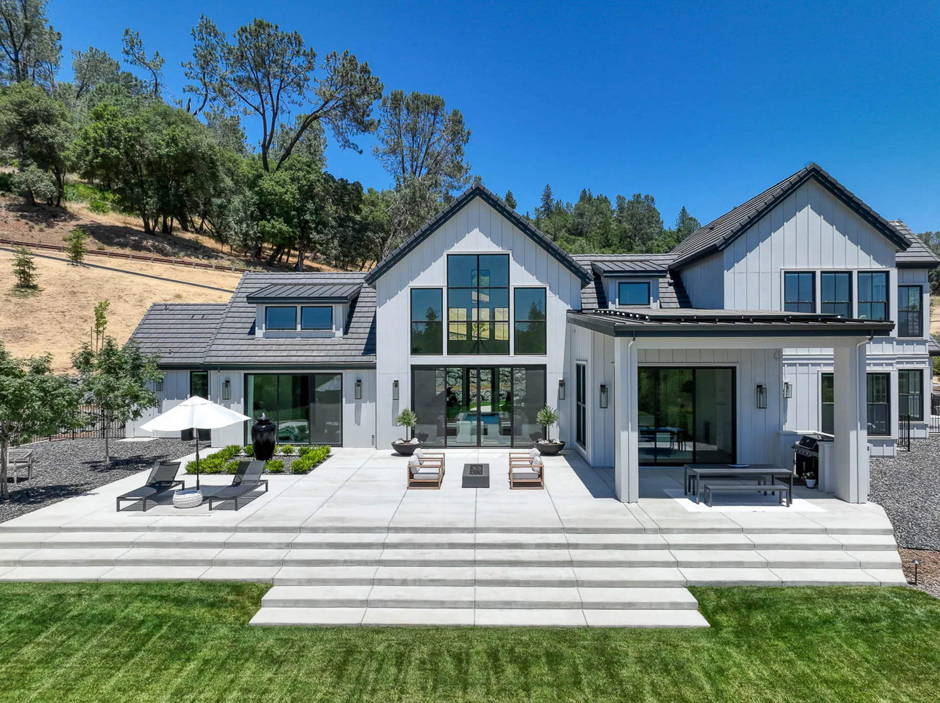 Back patio with lounge chairs and wide concrete steps down to the lawn at a Sherman custom home