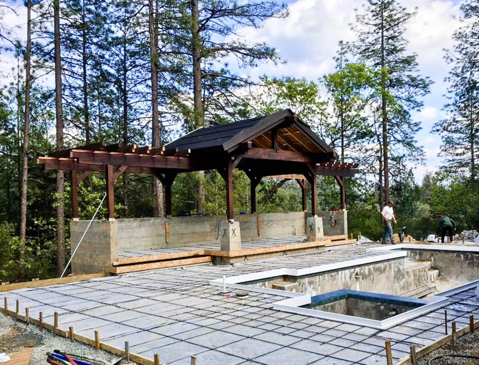 The timber pool pavilion during framing, with the pool shell and rebar in place