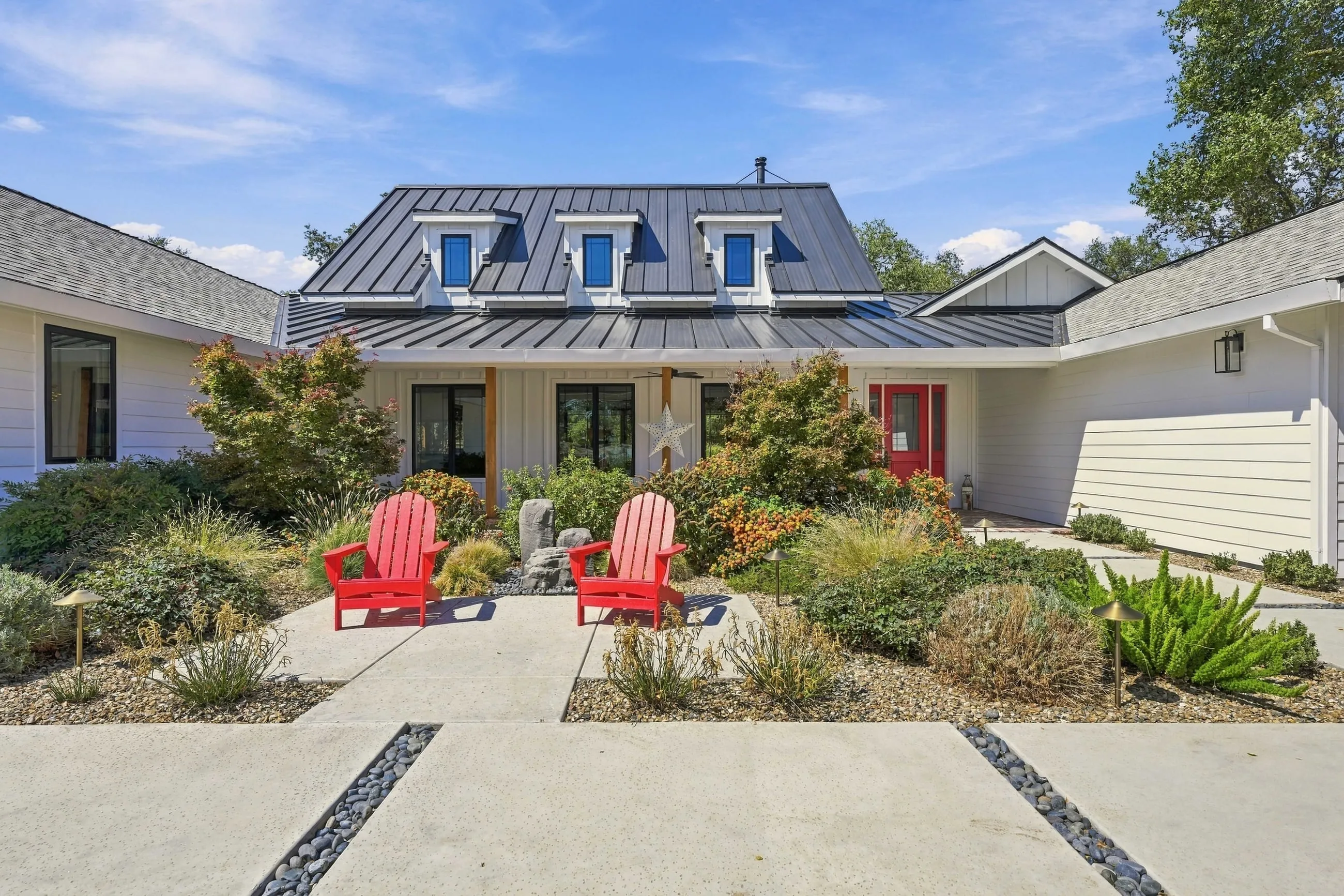Front courtyard garden with red chairs under a blue sky
