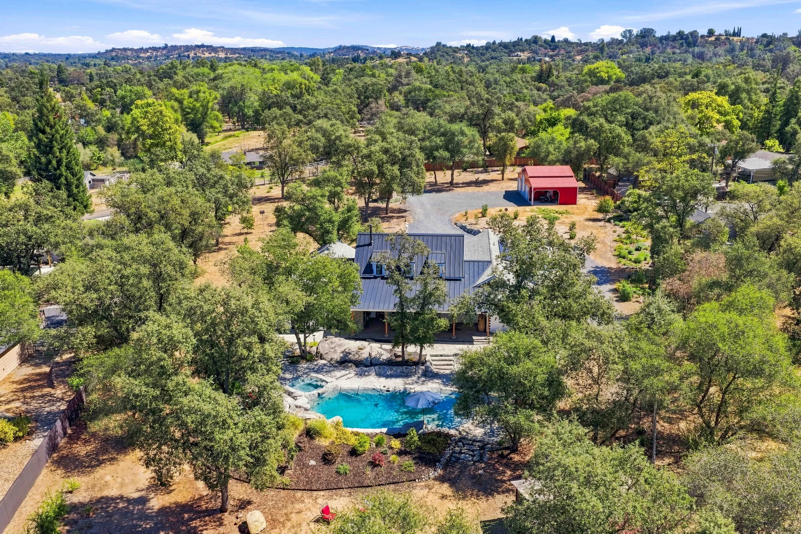 Aerial of the backyard and pool among the oaks with foothills beyond