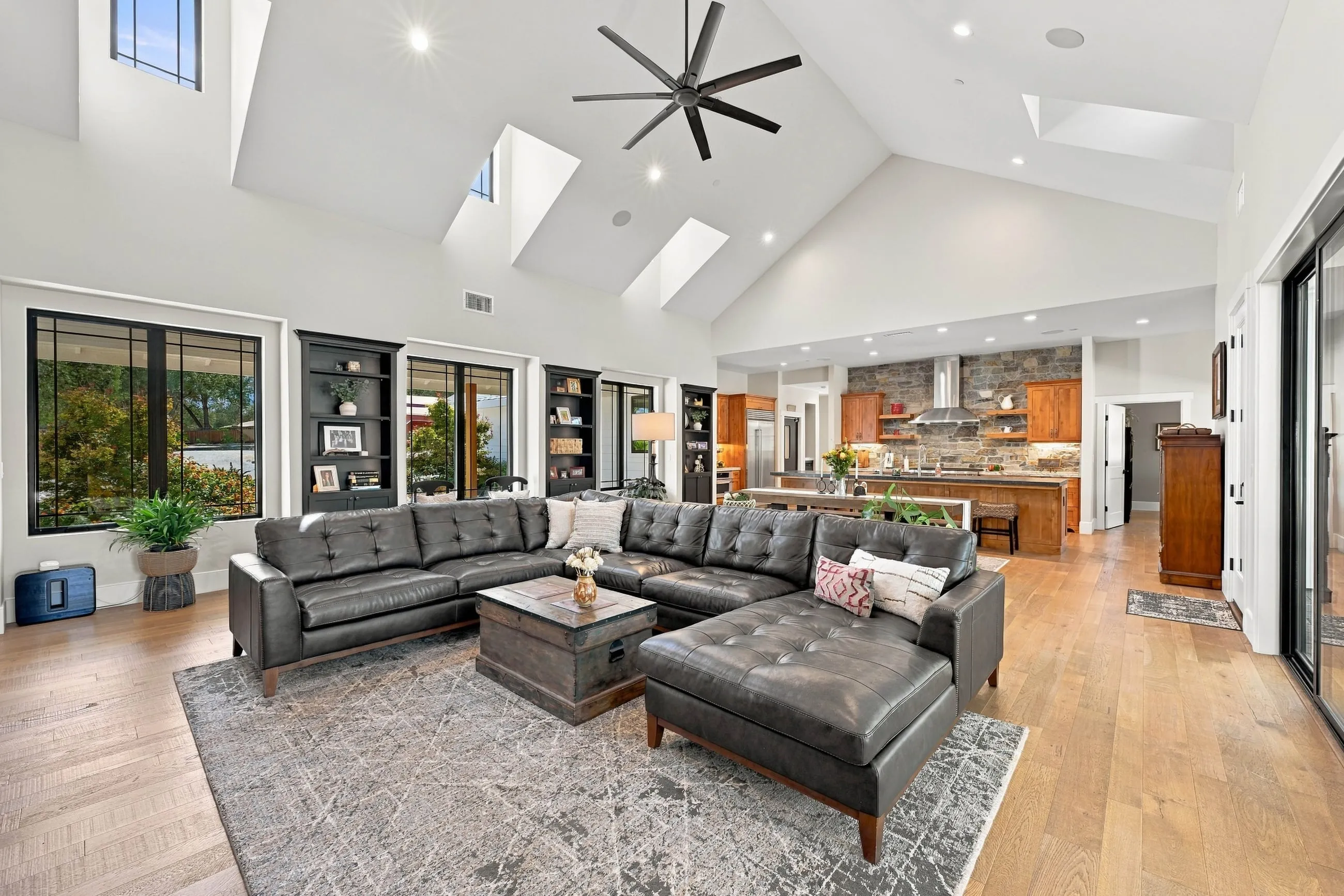 Great room looking toward the kitchen with vaulted ceiling, skylights, and black built-in bookcases