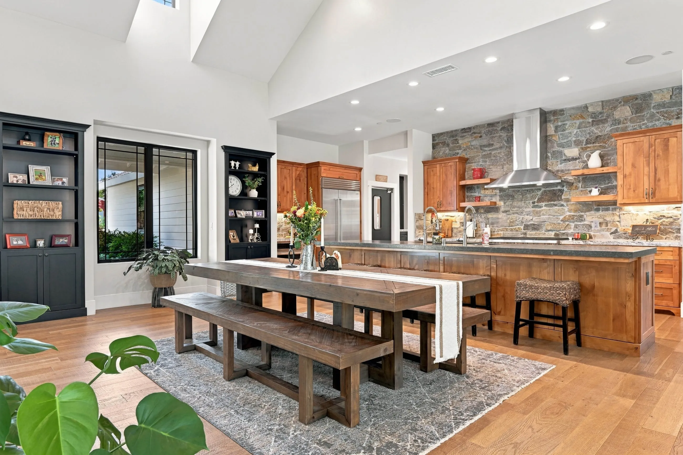 Open dining area with farmhouse trestle table and benches beside the kitchen