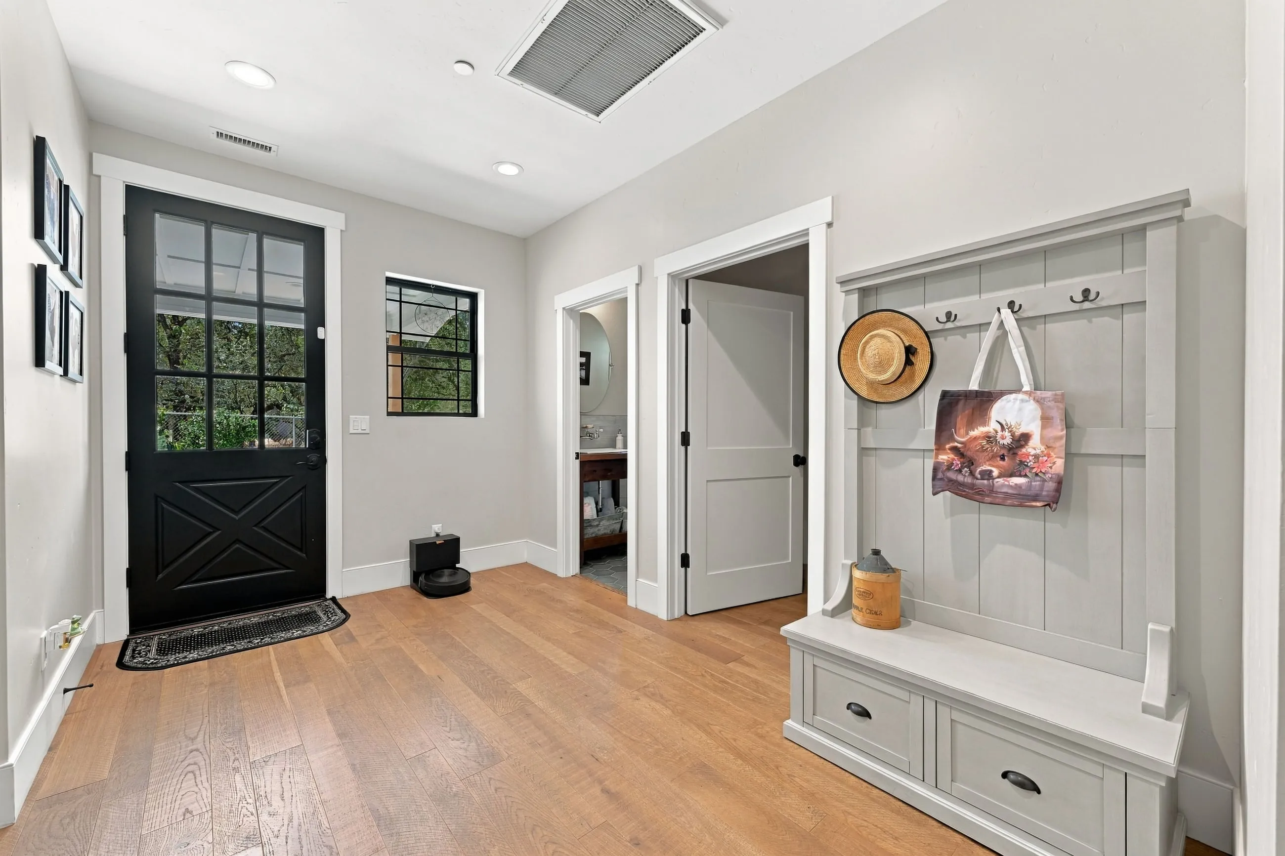 Mudroom with black crossbuck door and built-in bench with hooks