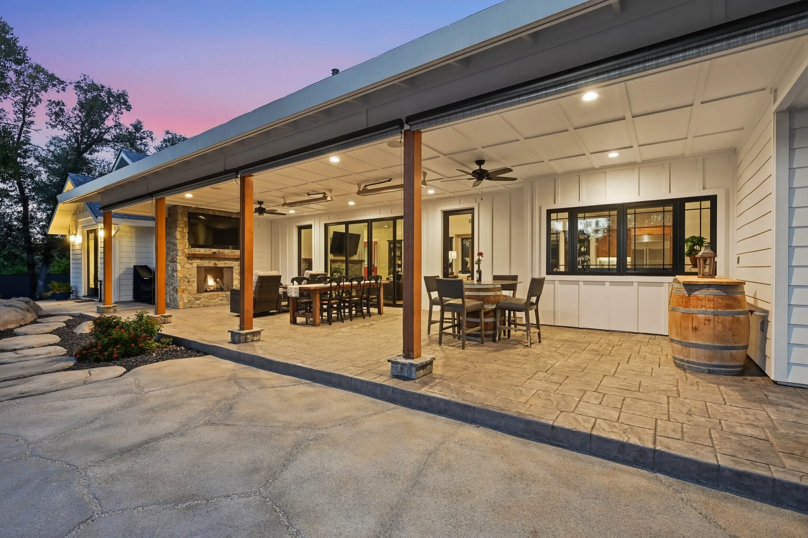 Covered back porch at dusk with wood posts, stamped concrete, and dining areas