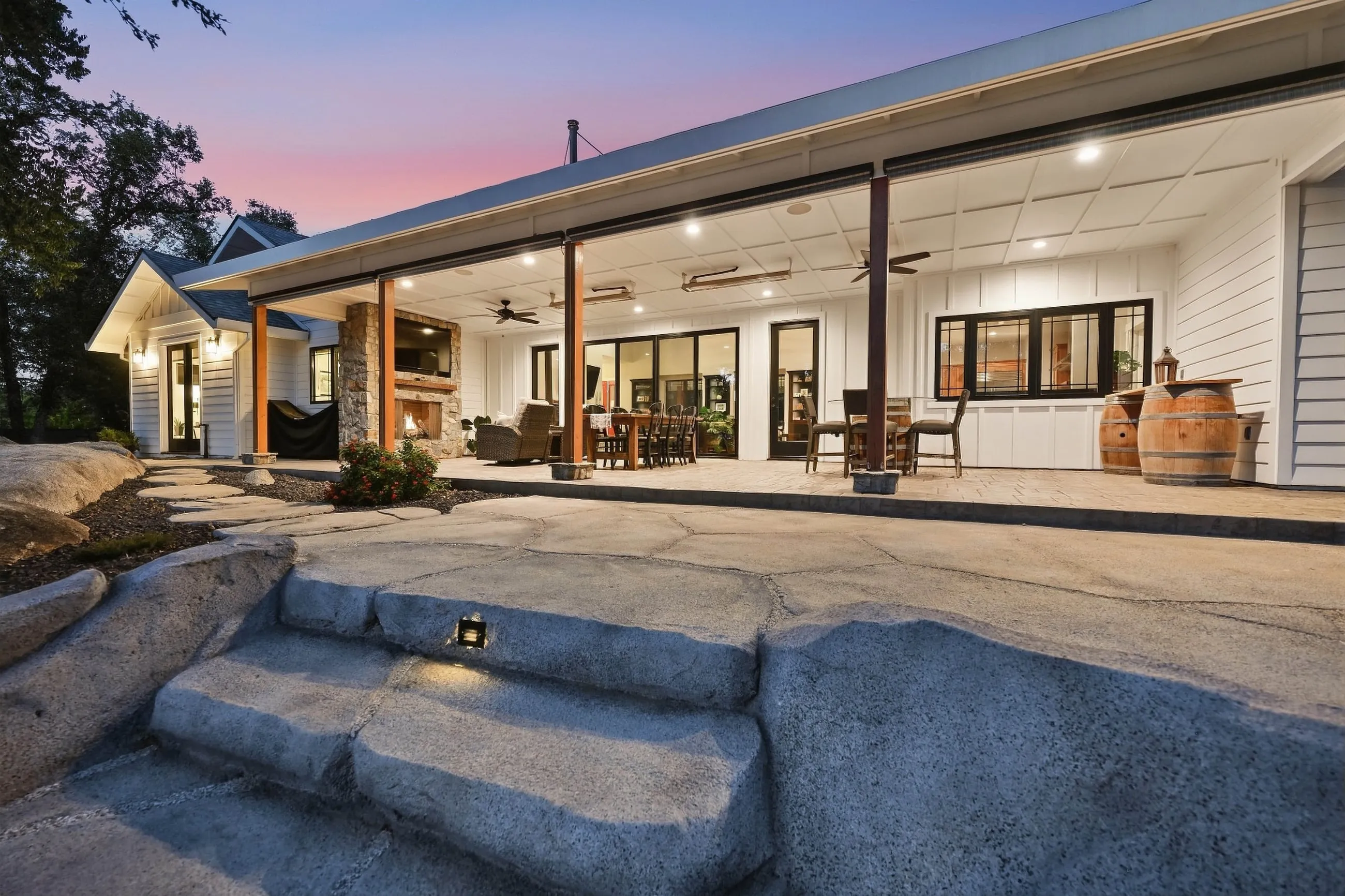 Full-length covered porch glowing at twilight above boulder steps