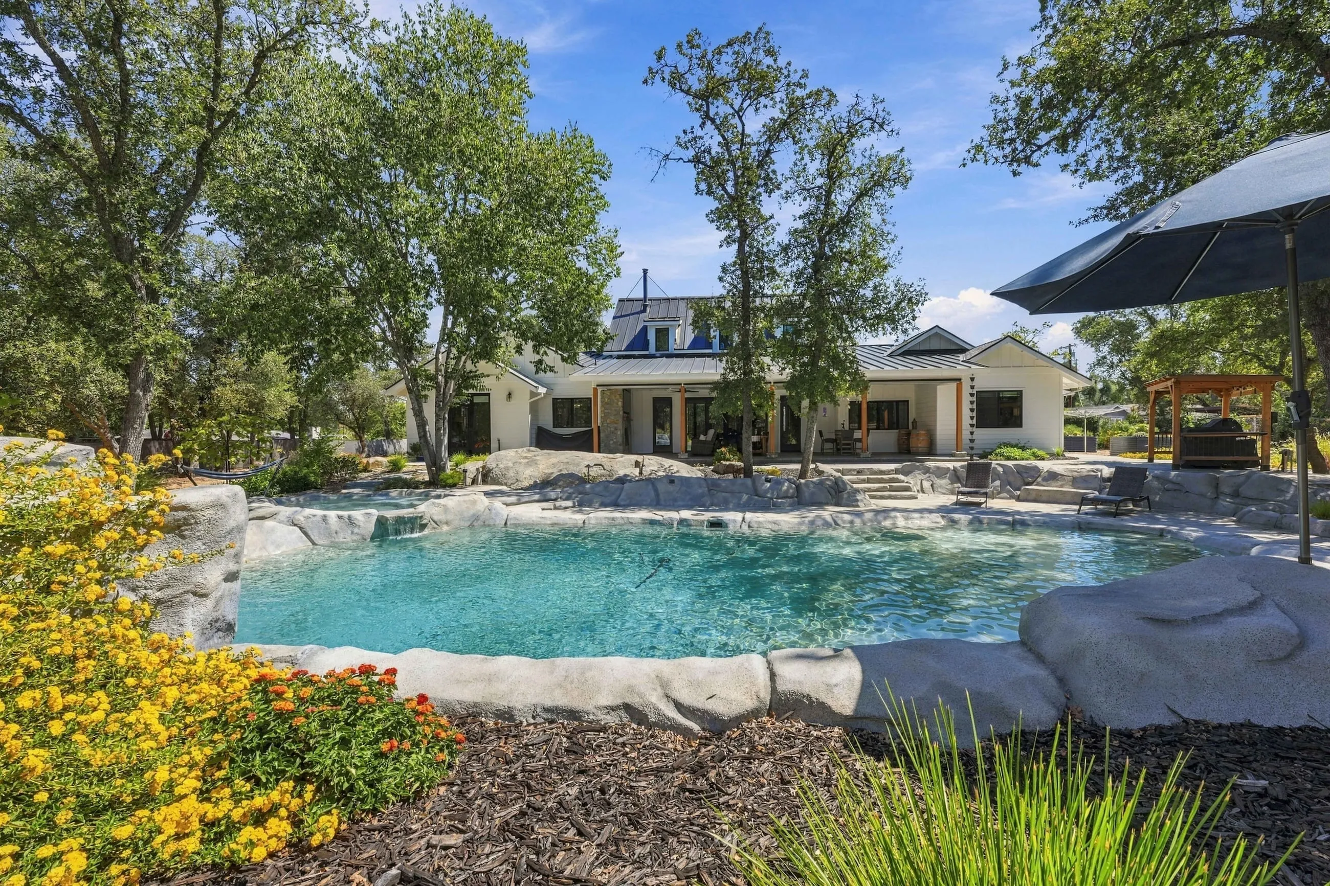 Lagoon pool by day with the home behind and flowering landscape