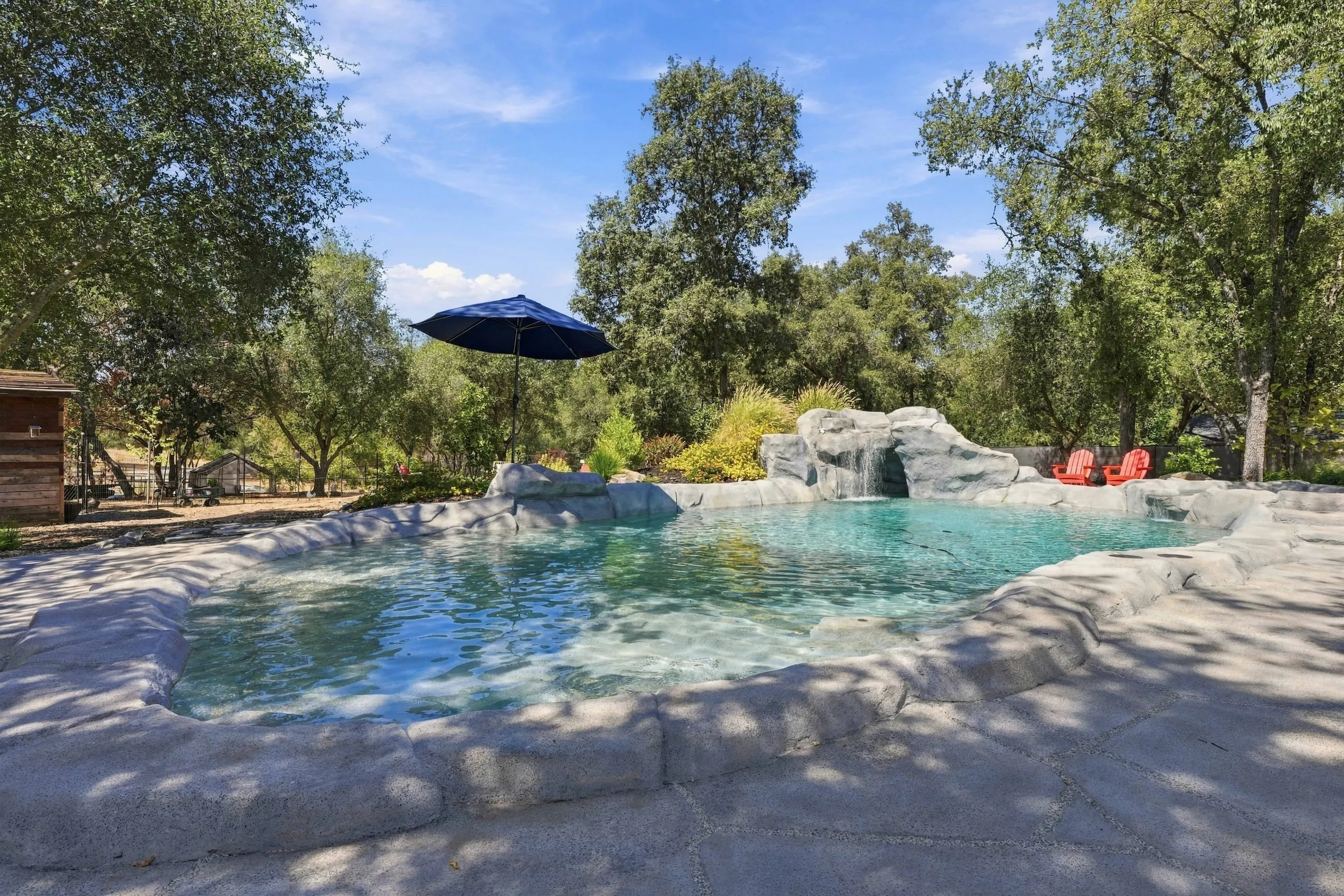 Freeform pool with rock waterfall beneath the oaks