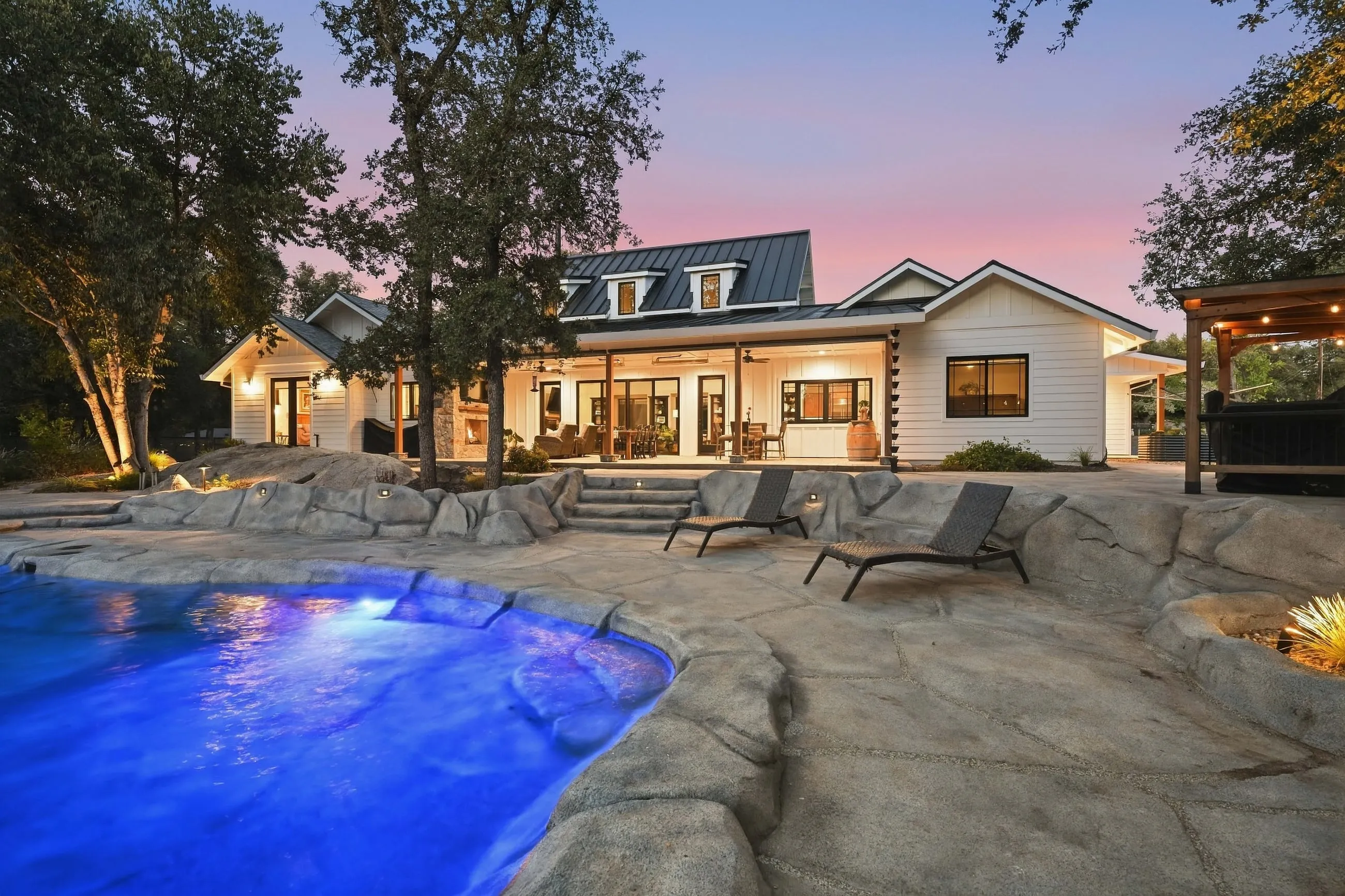 Pool steps and chaise lounges with the home glowing behind