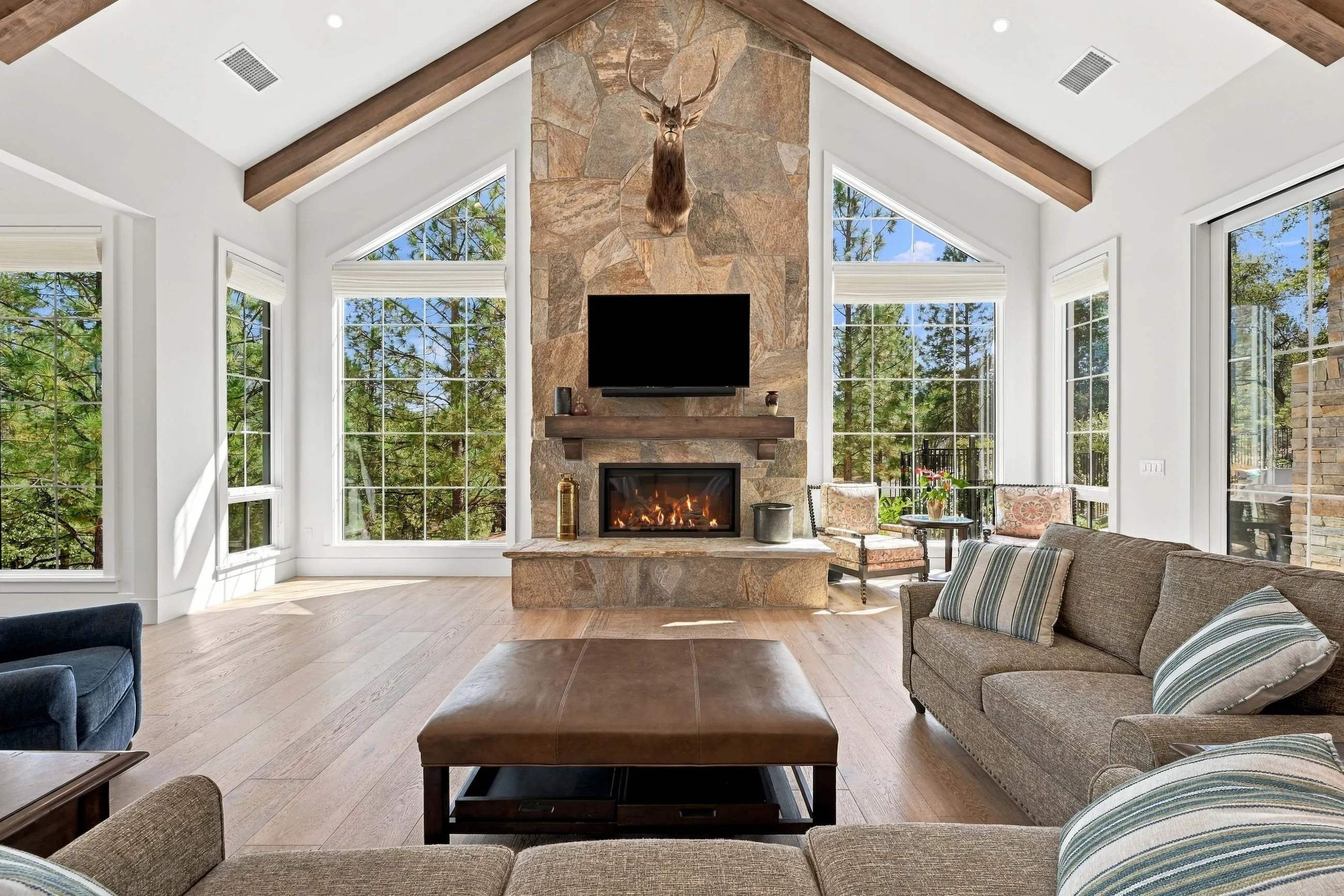 Vaulted great room with a floor-to-ceiling stone fireplace flanked by gable windows