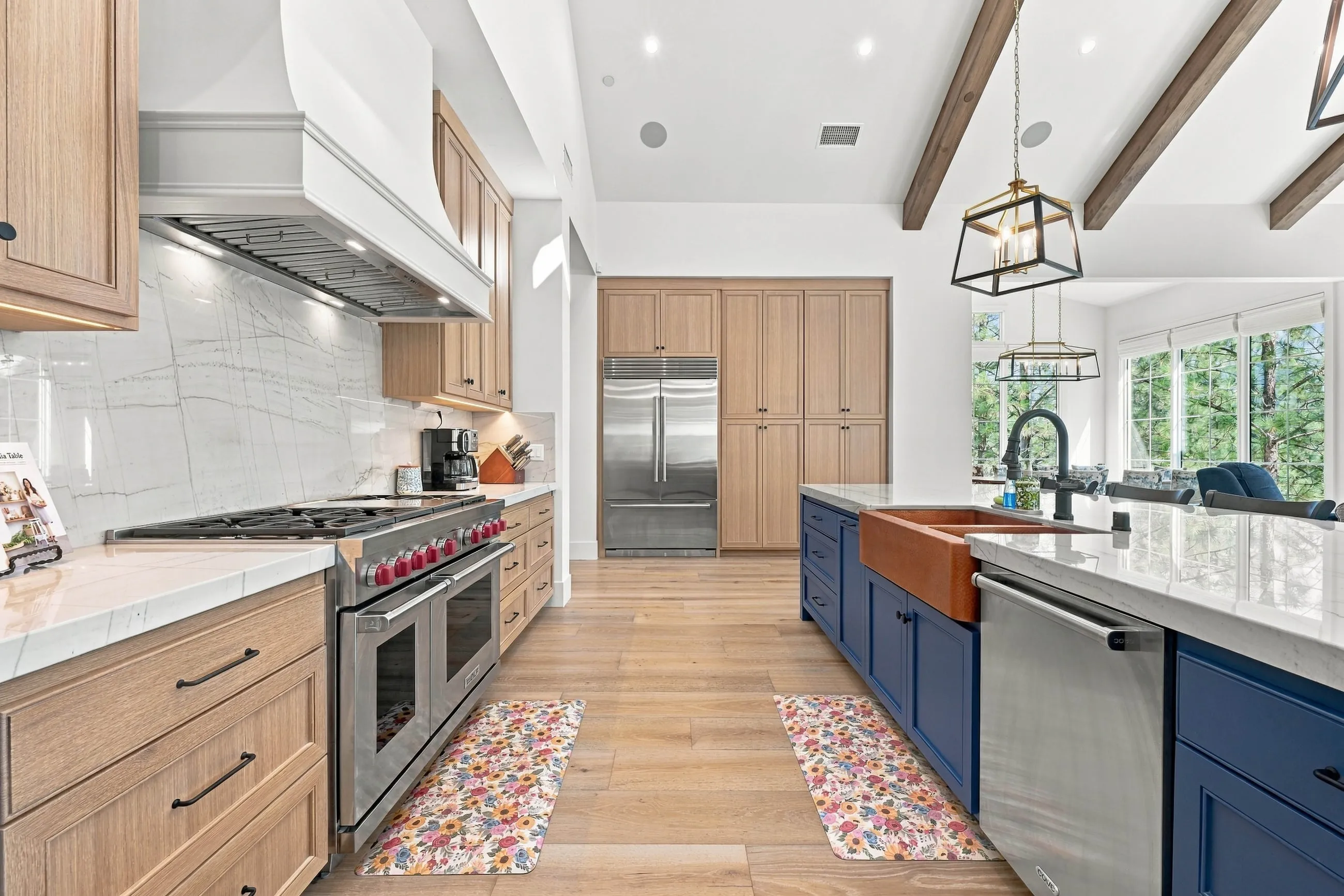 Professional range with double ovens, marble-look backsplash, and copper apron sink in the navy island