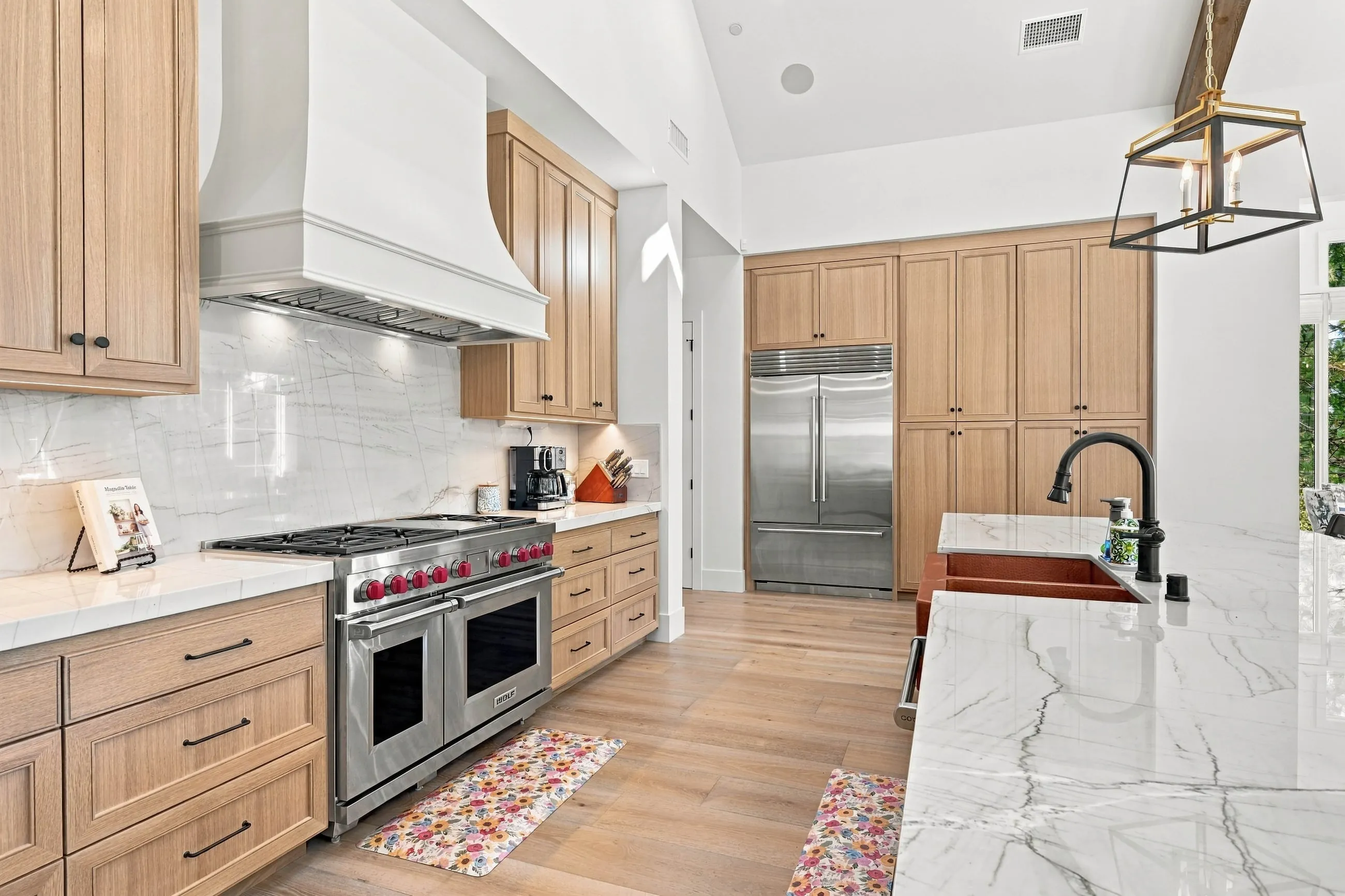 Kitchen range wall with white plaster hood, quartz counters, and oak cabinets
