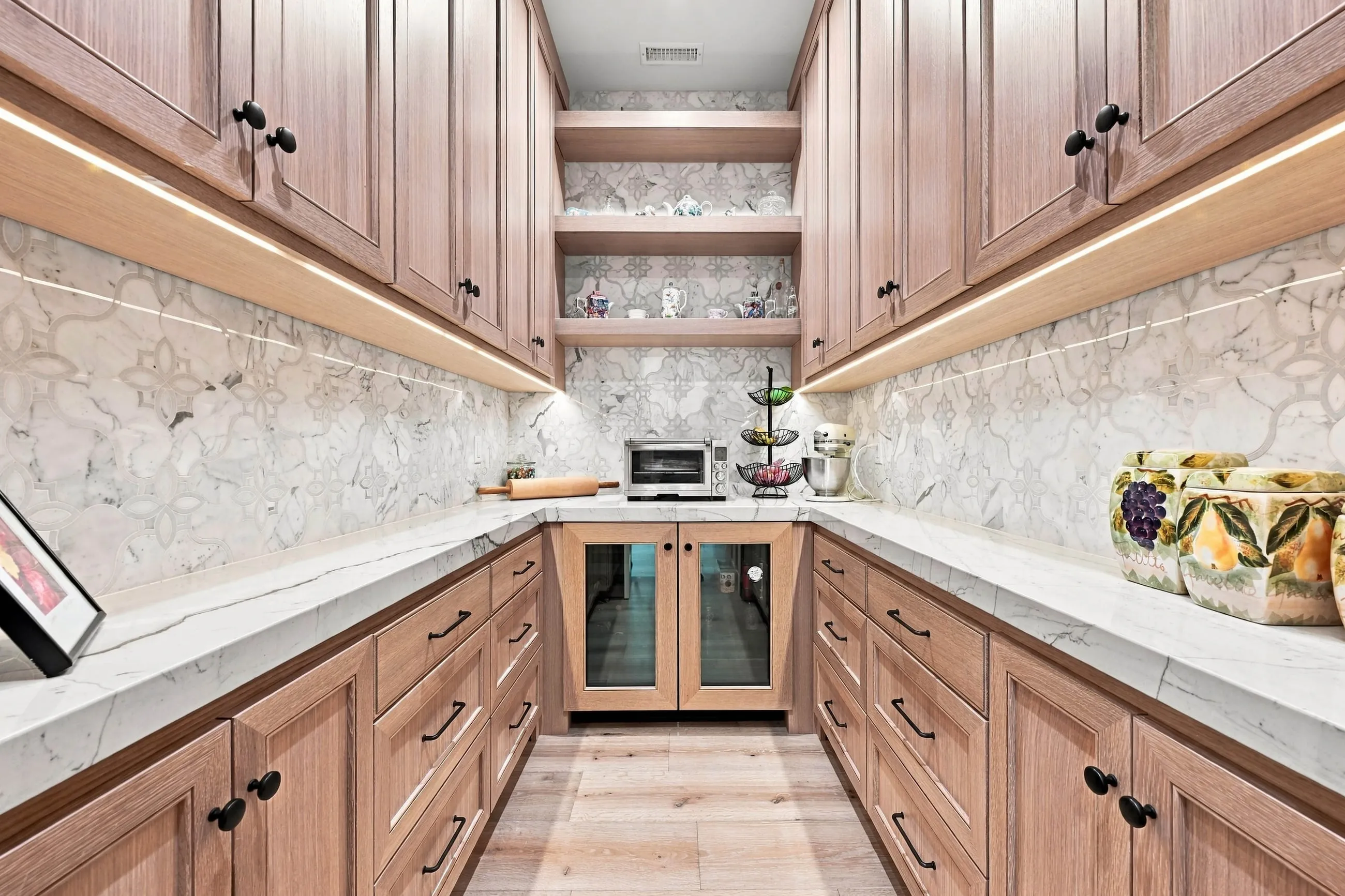 Butler's pantry with oak cabinetry, mosaic marble backsplash, and twin beverage coolers