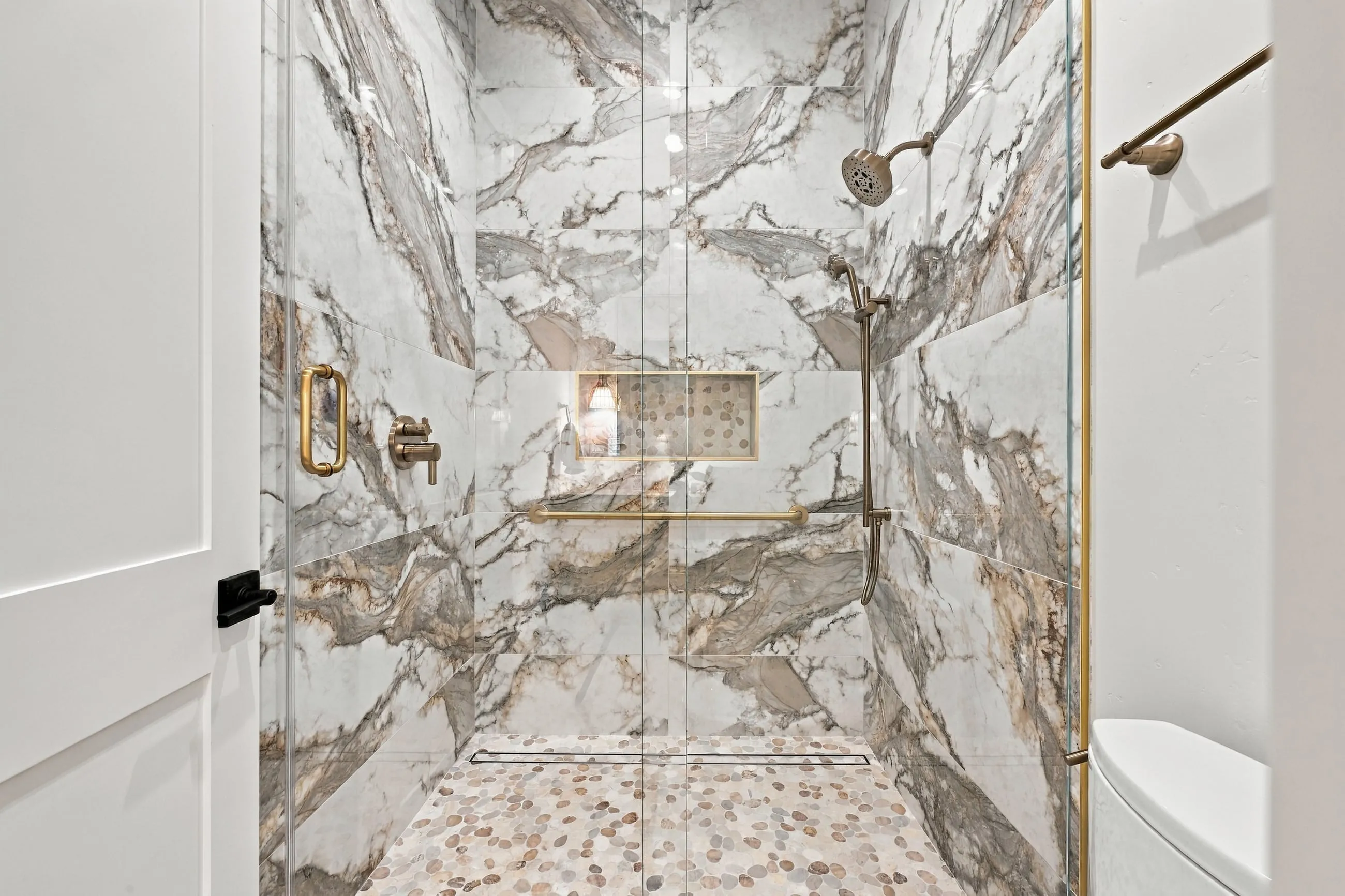 Guest shower in dramatic veined porcelain with brass fixtures