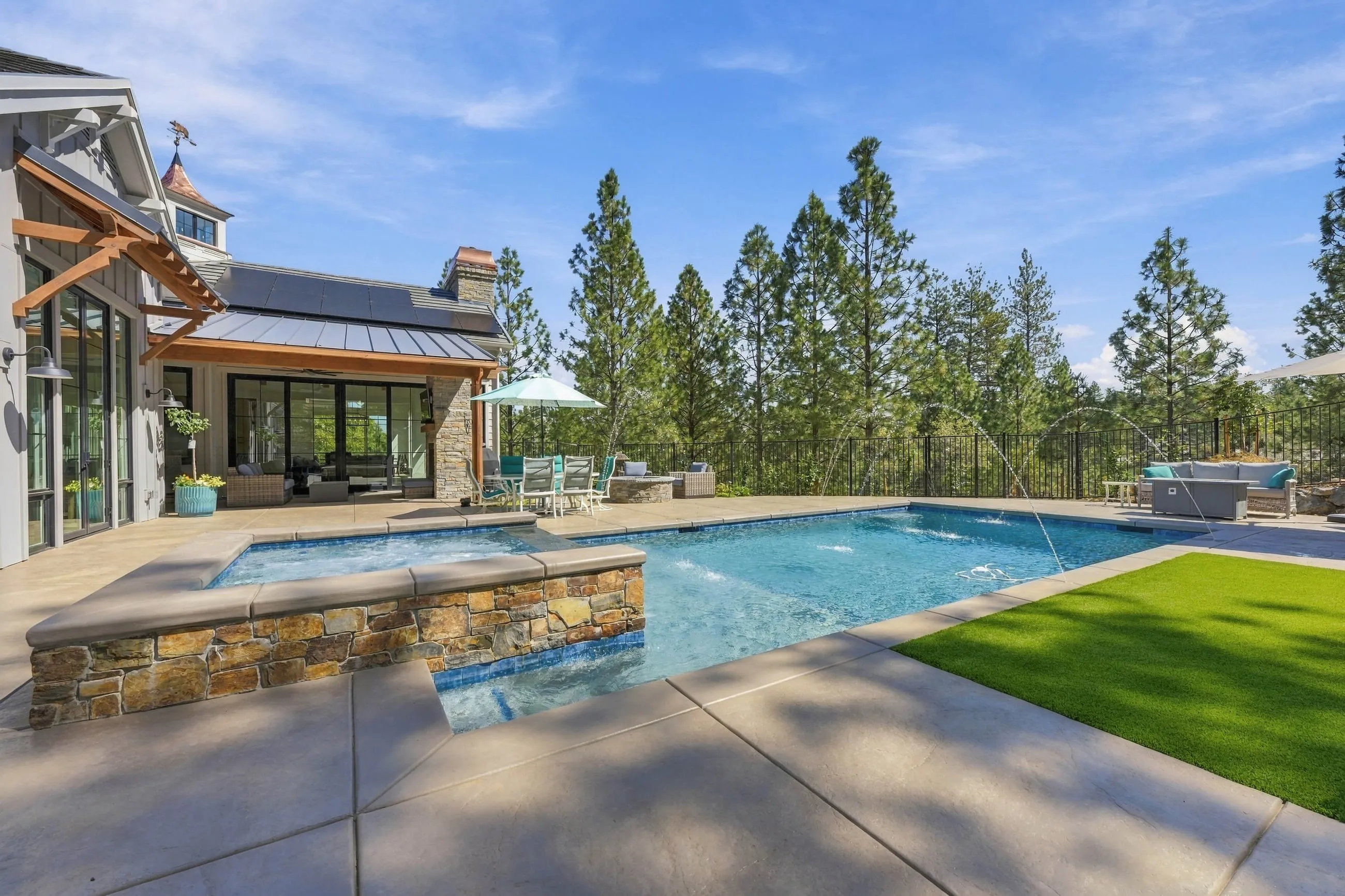 Raised stone spa and pool bordered by turf on a sunny day