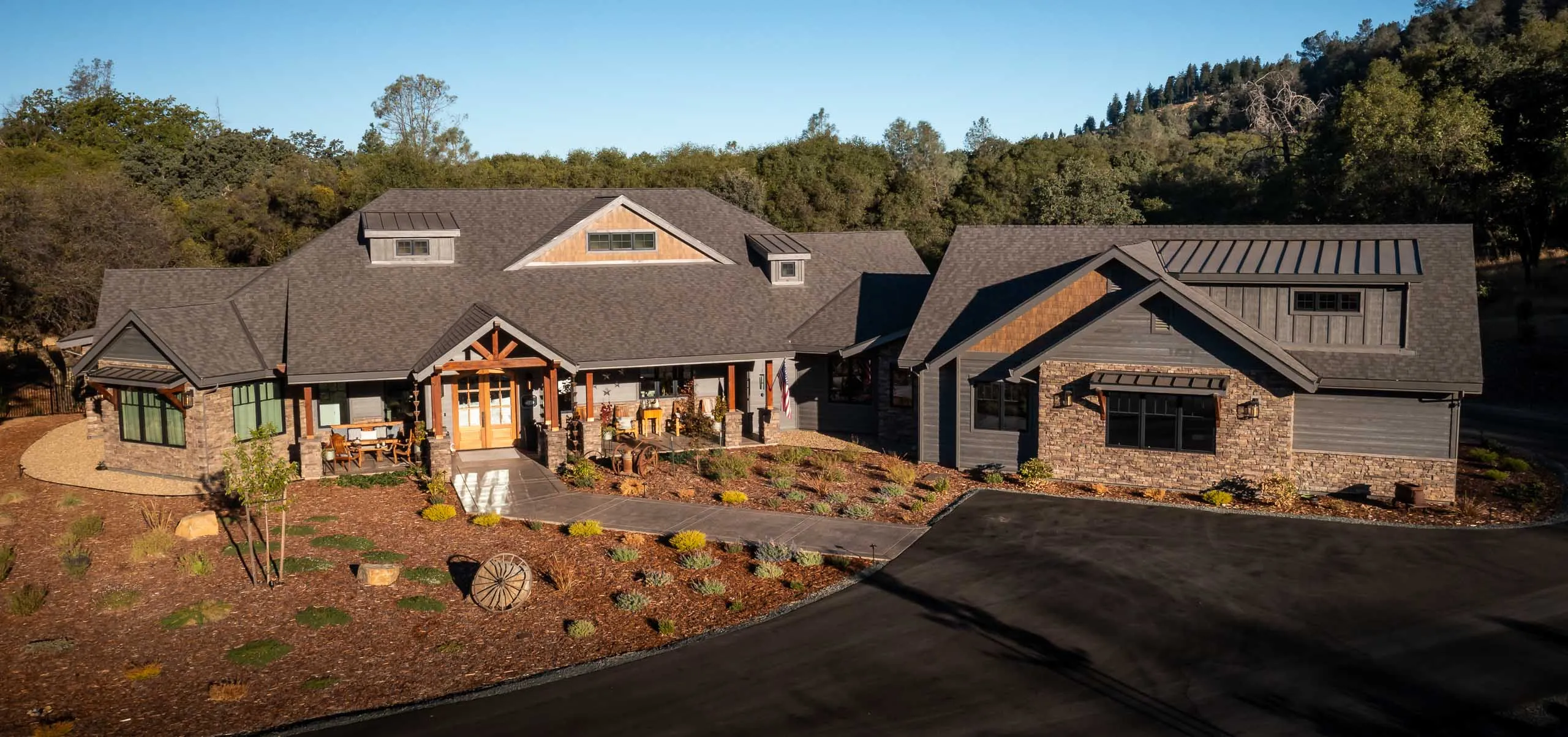 Aerial view of a sprawling ranch home with stone and shake gables tucked among oaks near Auburn