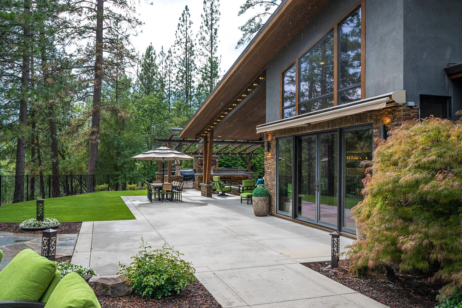 Wide concrete patio along the back of the home leading to outdoor dining and the lawn