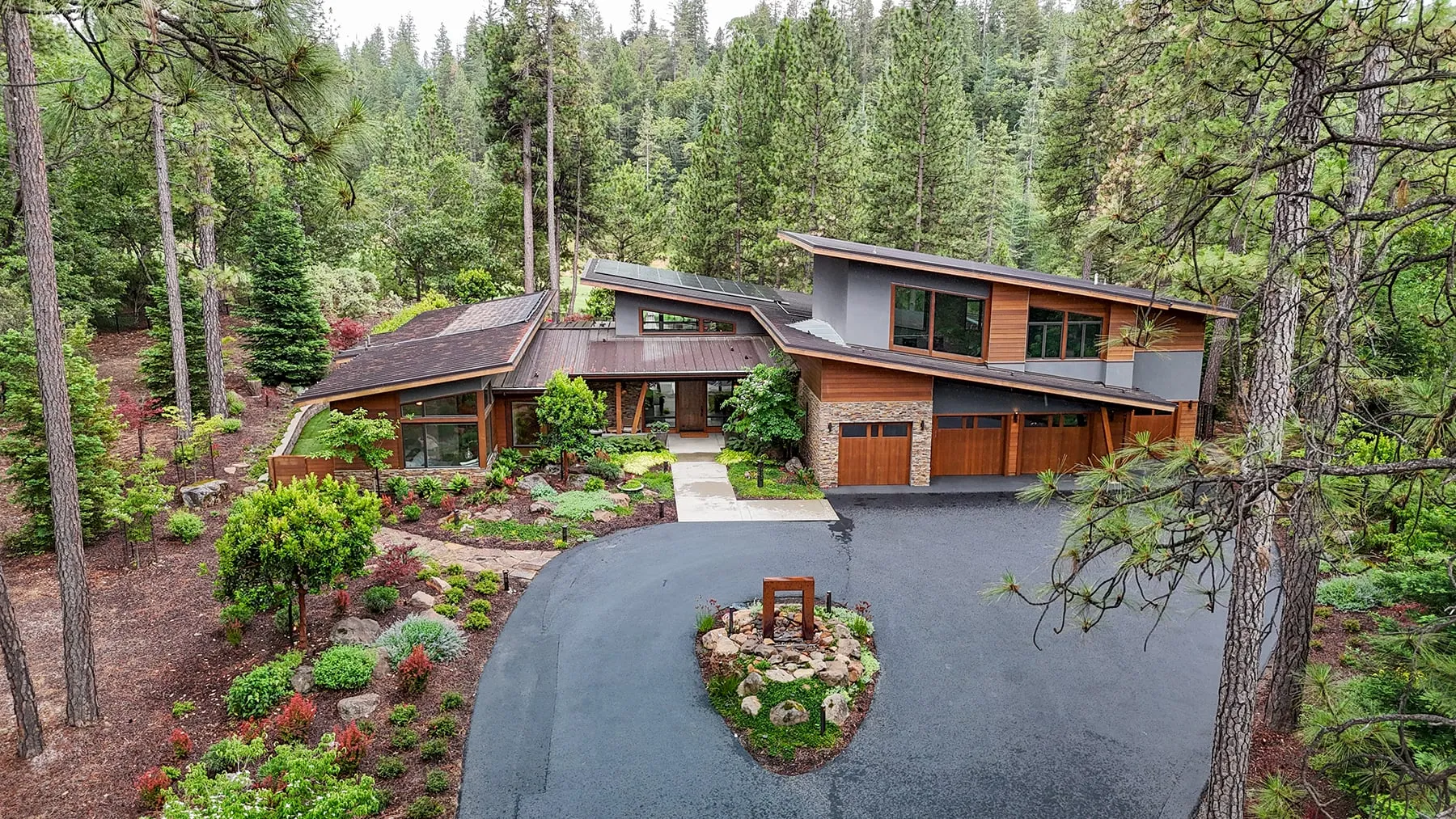 Aerial view of the front drive and sculpture island with the home set back in the pines