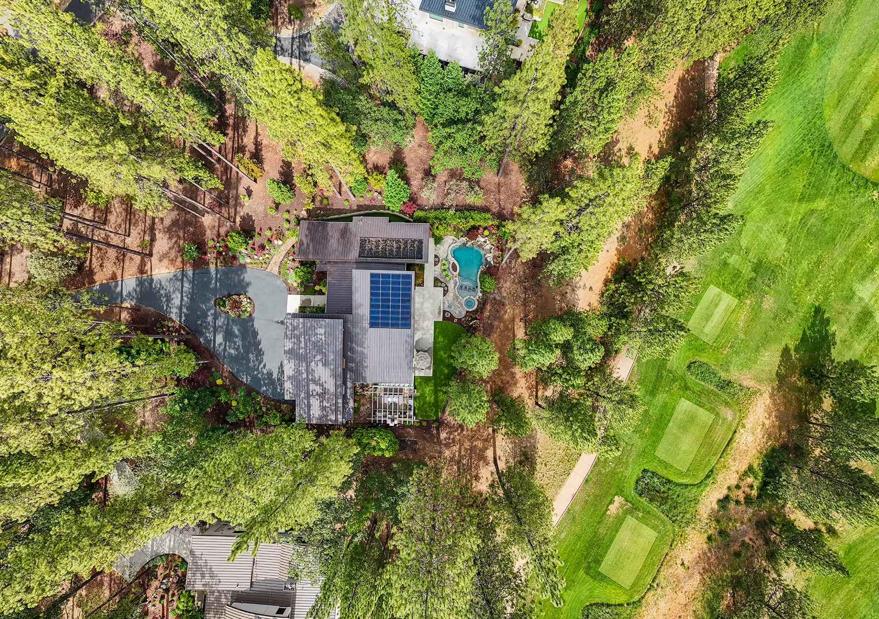 Overhead aerial of the home among the pines with the golf course tee boxes alongside