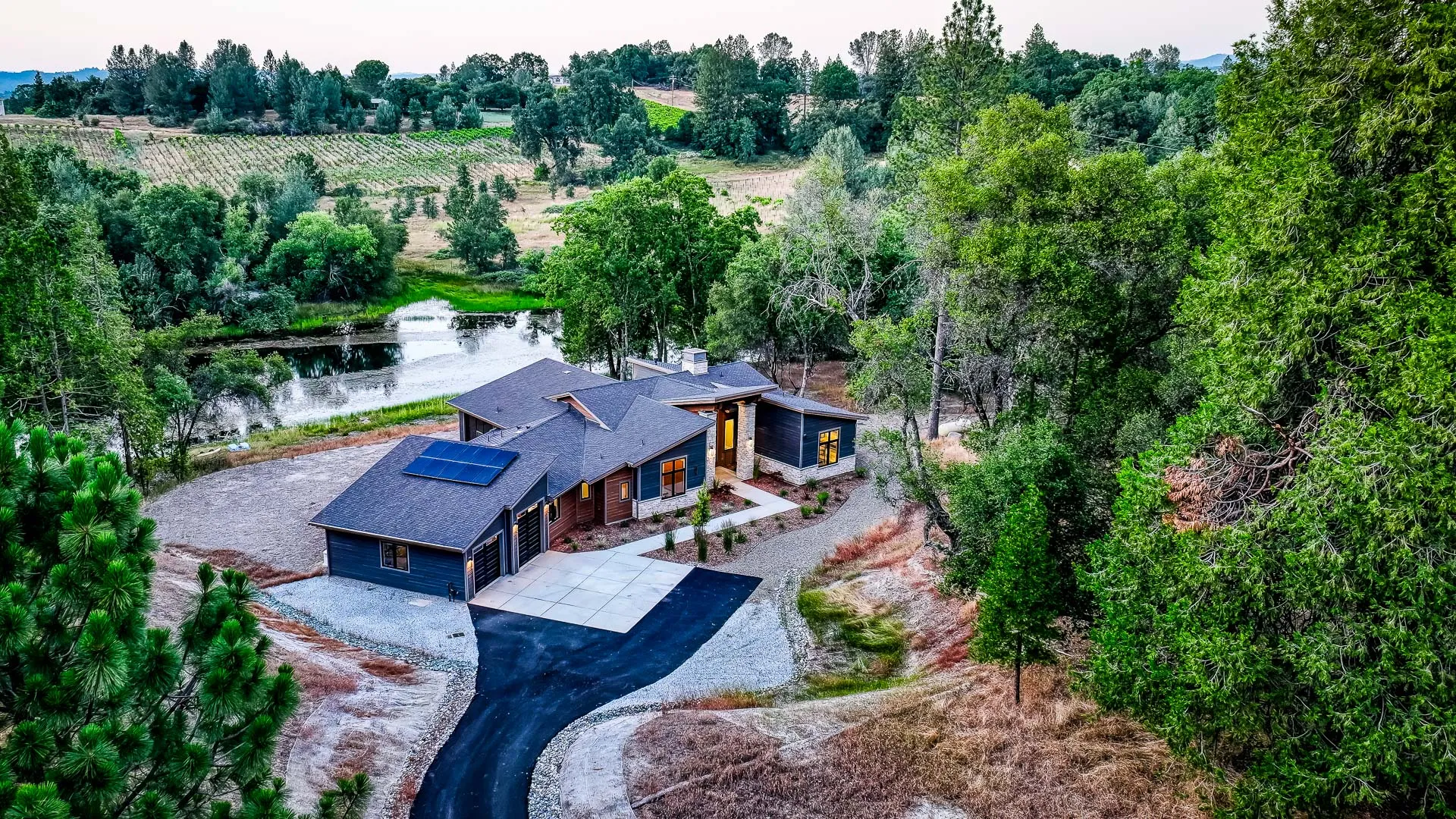 Evening aerial of the solar-equipped home overlooking the pond, vineyards, and rolling Gold Country hills