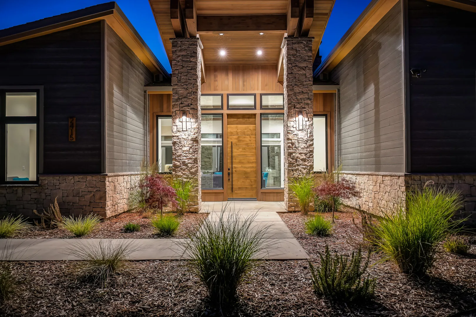 Modern foothill retreat at dusk with its pool terrace lit below