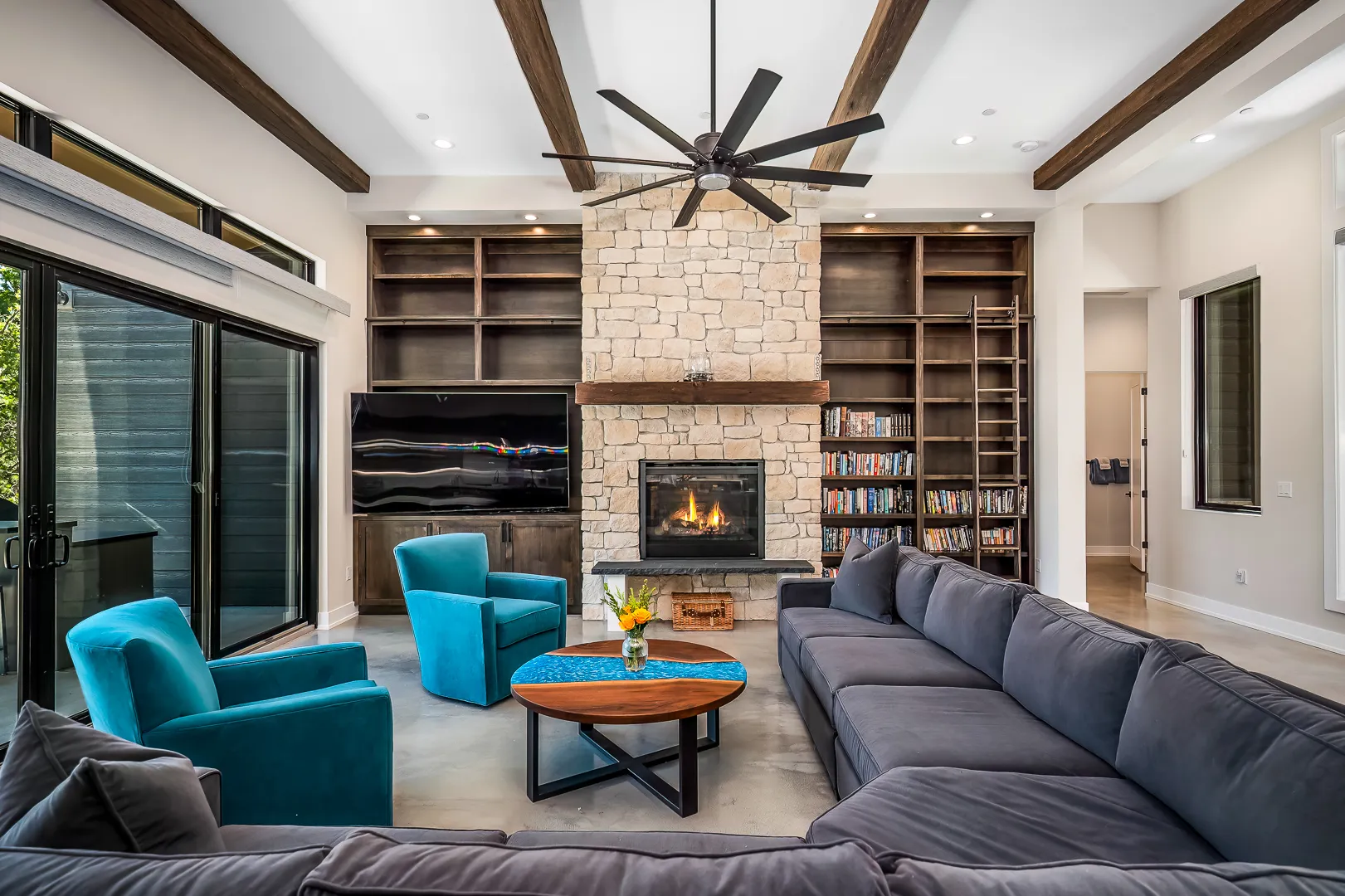 Living room with teal armchairs, live-edge coffee table, and stone fireplace