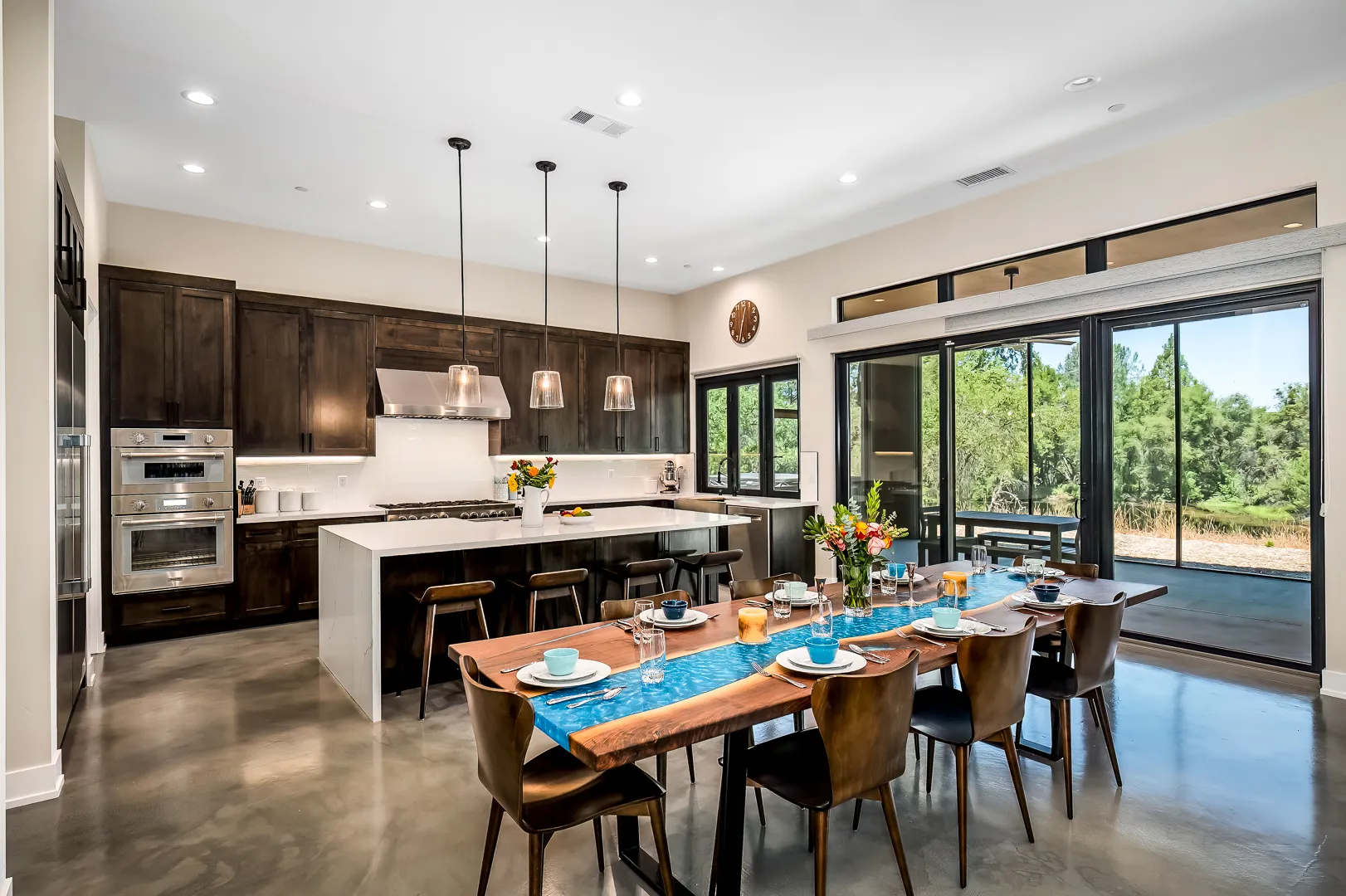 Open kitchen and dining room with a walnut table and dark cabinetry in a Sherman custom home
