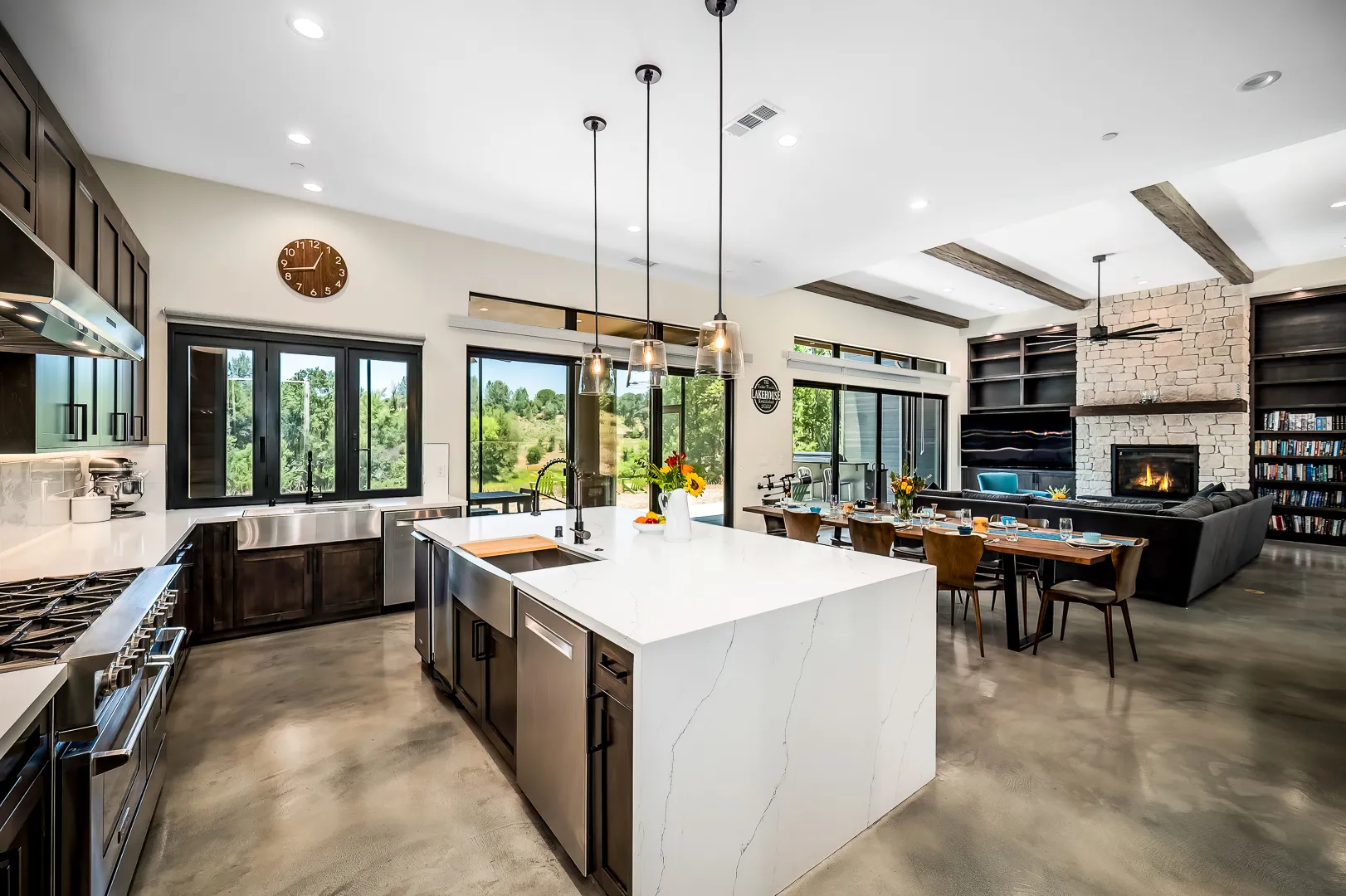 Waterfall-edge quartz island with farmhouse sink, looking across the open plan to the stone fireplace