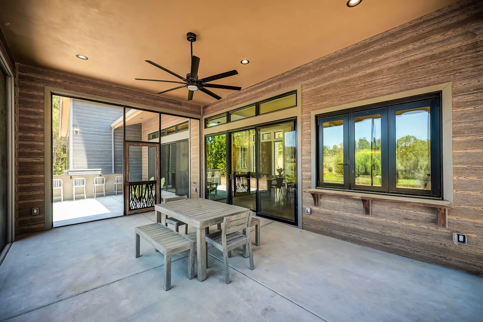 Covered patio with dining table and stone fireplace at a Sherman custom home