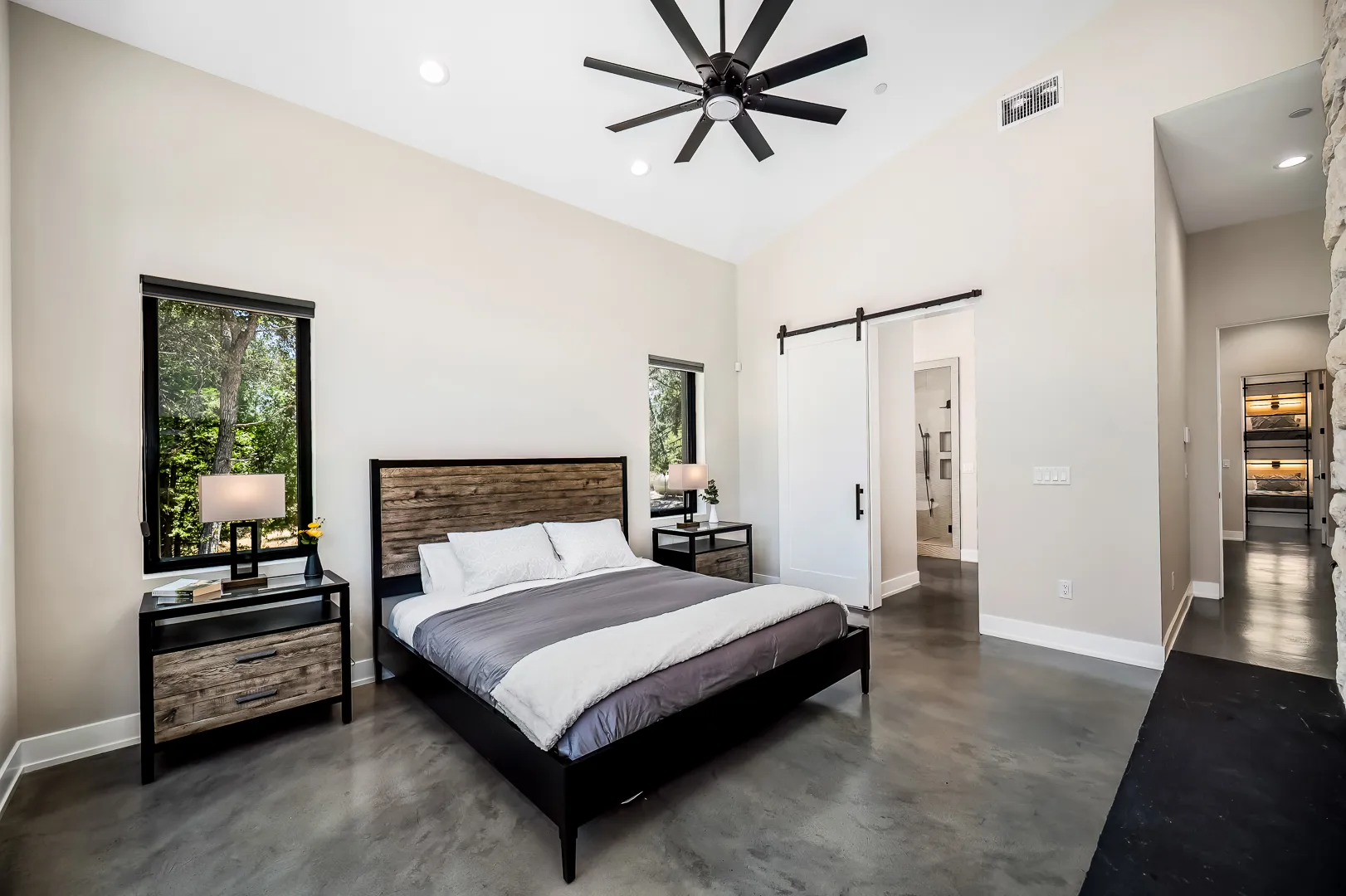 Guest bedroom with reclaimed-wood headboard, vaulted ceiling, and sliding barn door to the bath