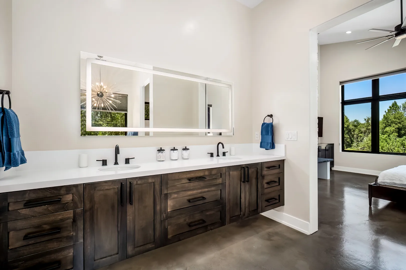 Primary bath with long floating double vanity, backlit mirror, and matte black fixtures