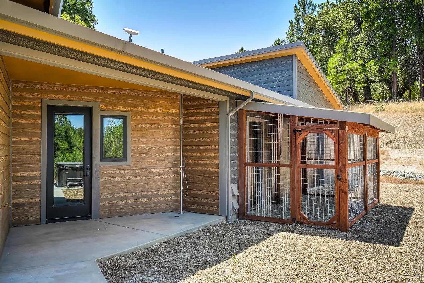 Outdoor shower on the back patio beside a custom covered dog run with welded-wire panels