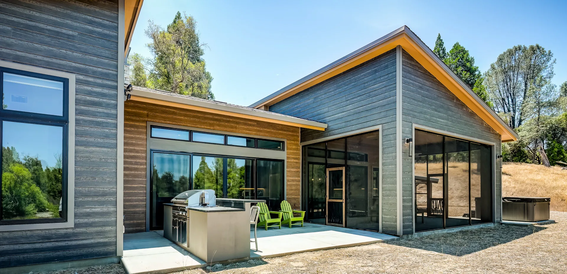 Back patio with stainless grill island, screened porch, and hot tub beyond the glass walls
