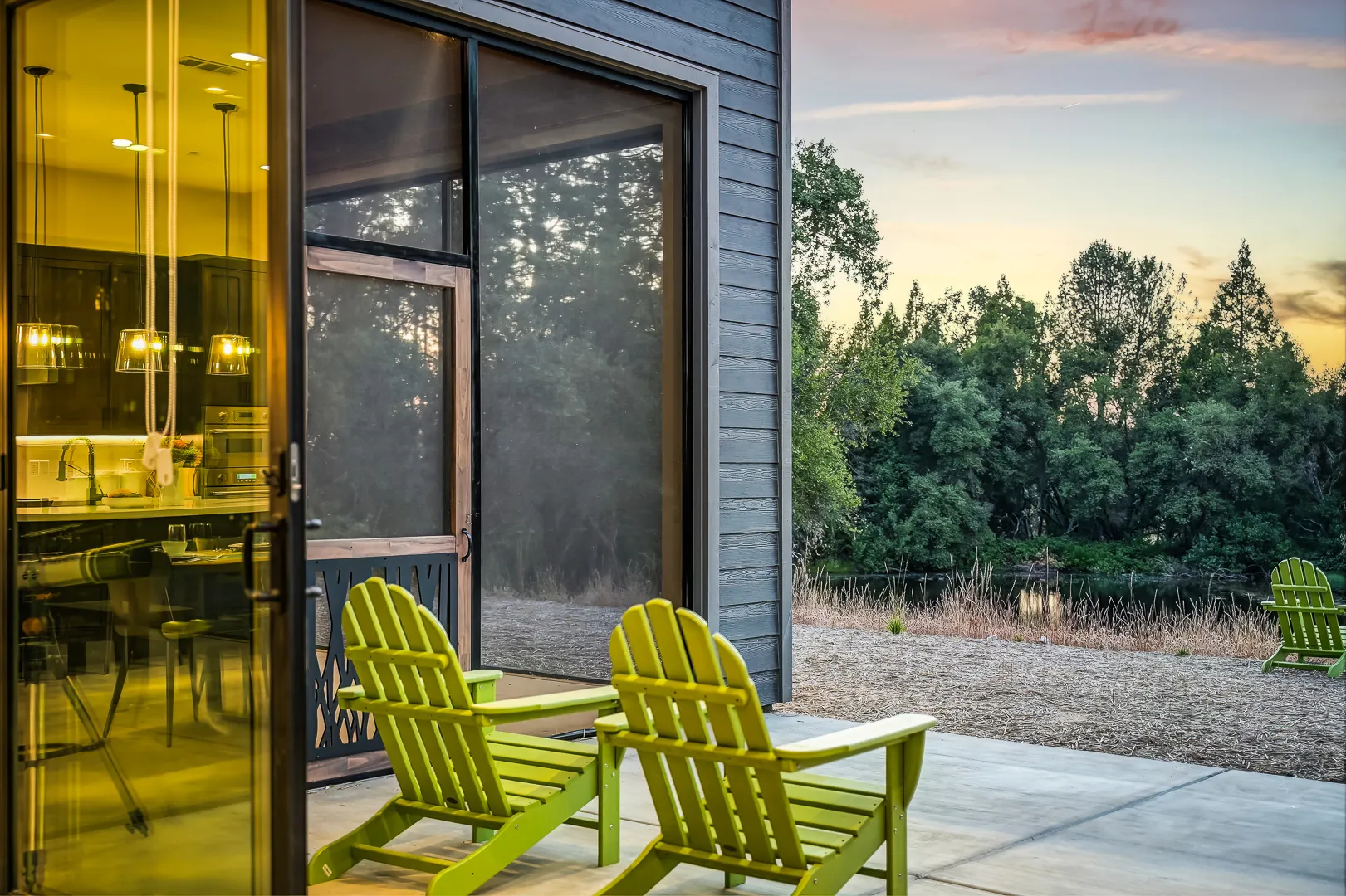 Sunset on the patio, Adirondack chairs beside the screened porch with the kitchen glowing inside
