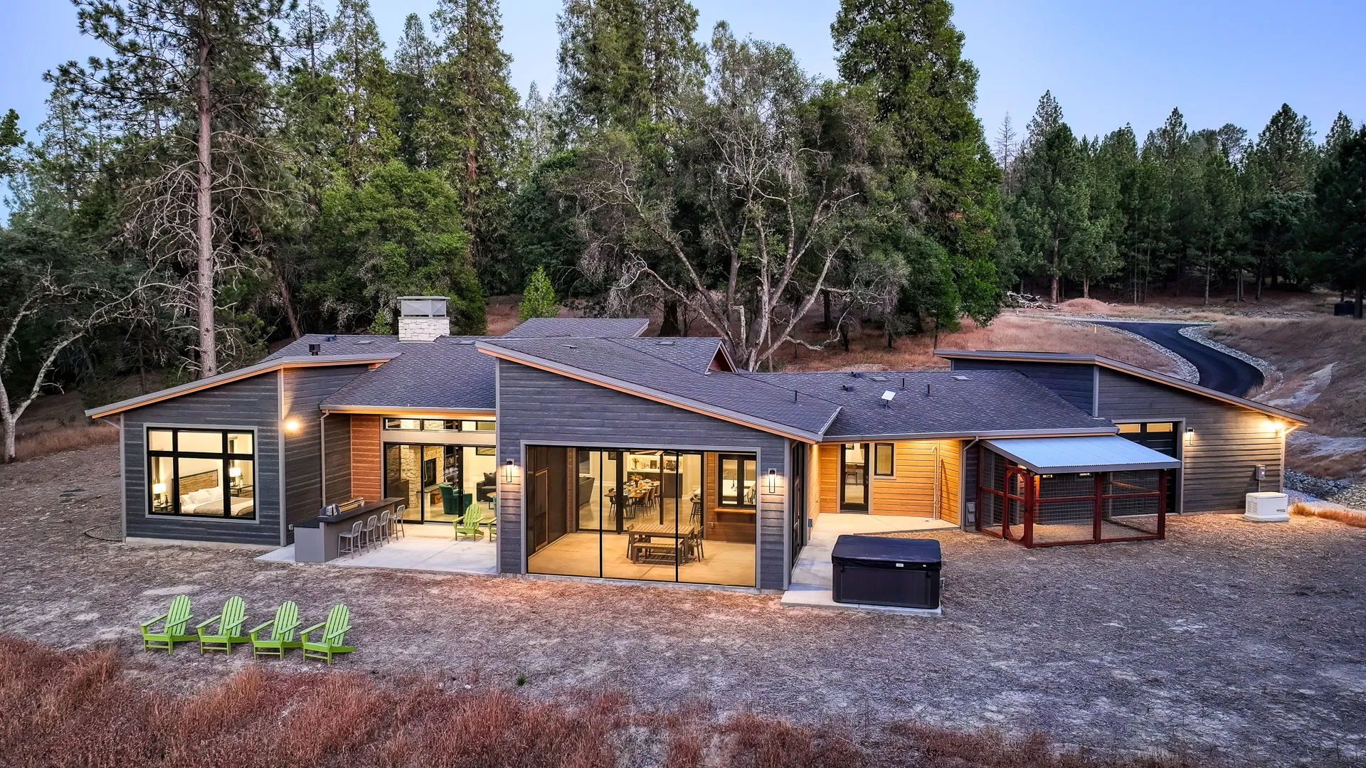 Evening aerial of the back patios with outdoor bar, hot tub, and covered dog run