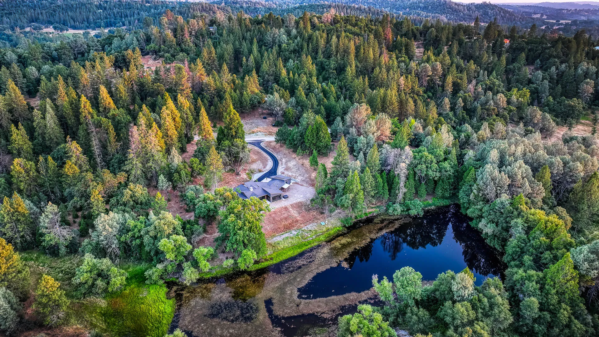 High aerial of the retreat nestled in Gold Country forest at the edge of its pond
