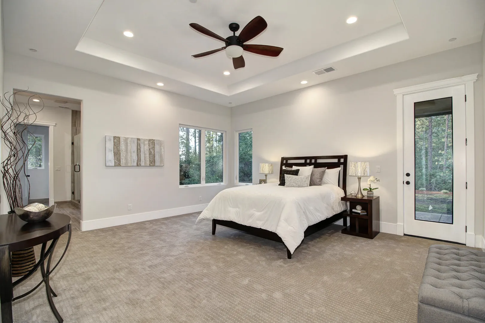 Spacious primary bedroom with tray ceiling, ceiling fan, and a glass door to the backyard