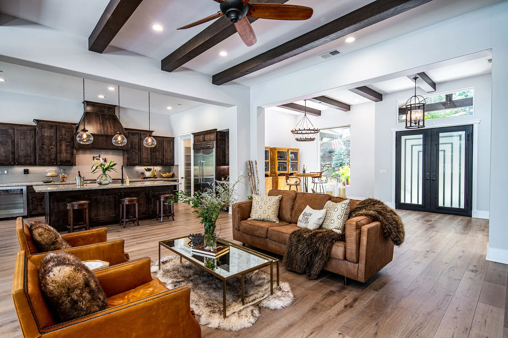 Great room with leather sofas, beamed ceiling, and iron-and-glass double front doors