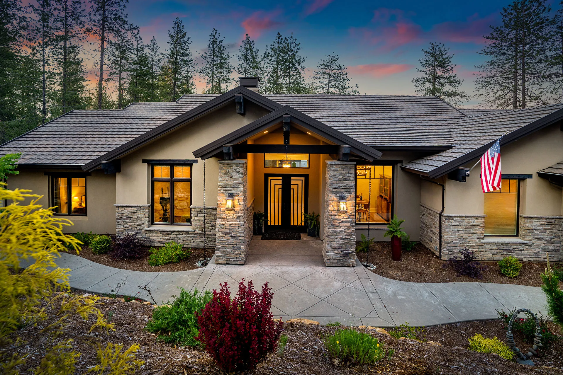 Sunset front elevation in Meadow Vista, California, with stacked-stone entry columns and glowing windows