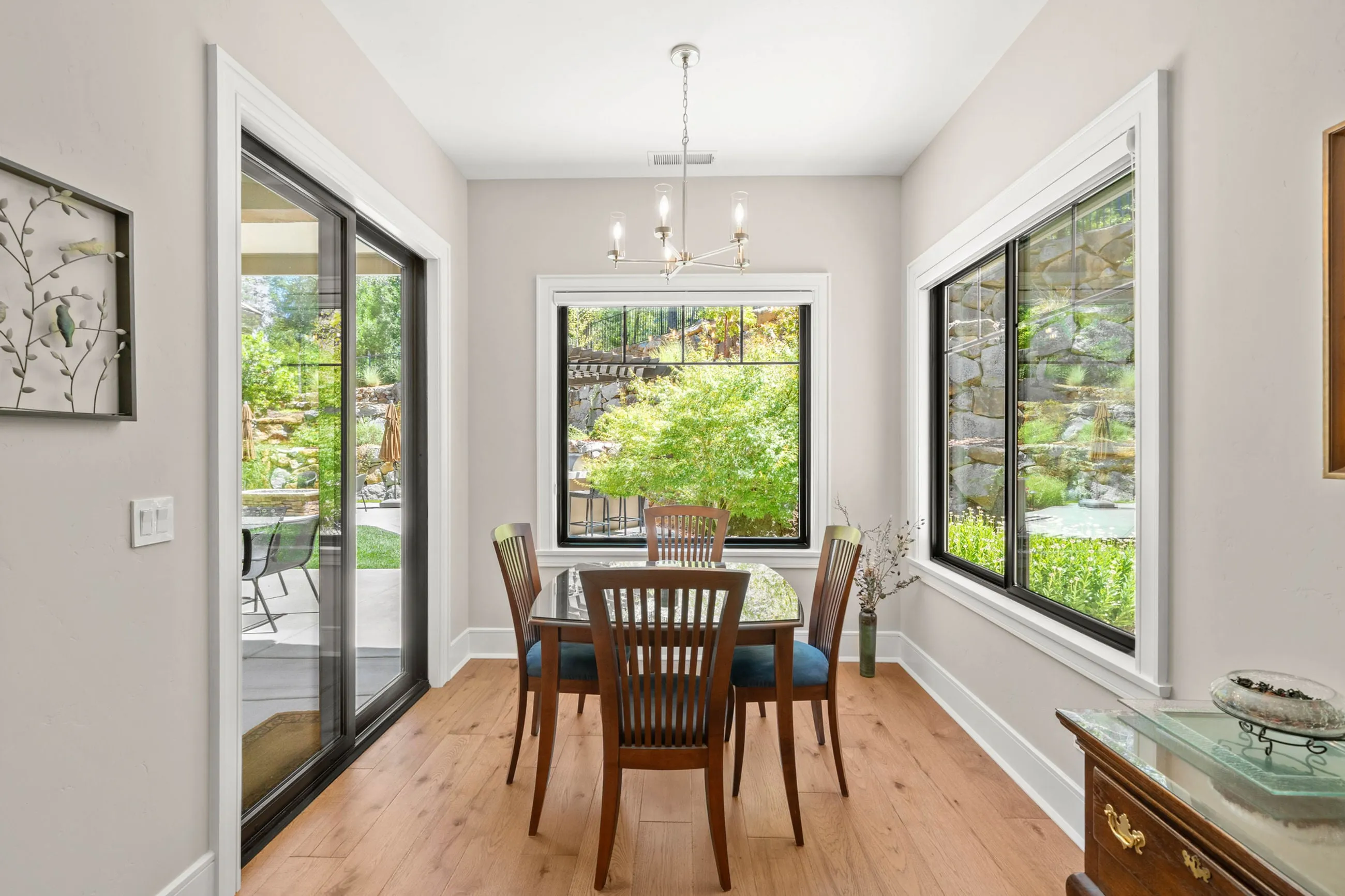 Breakfast nook with a slider and corner windows framing the boulder retaining wall outside