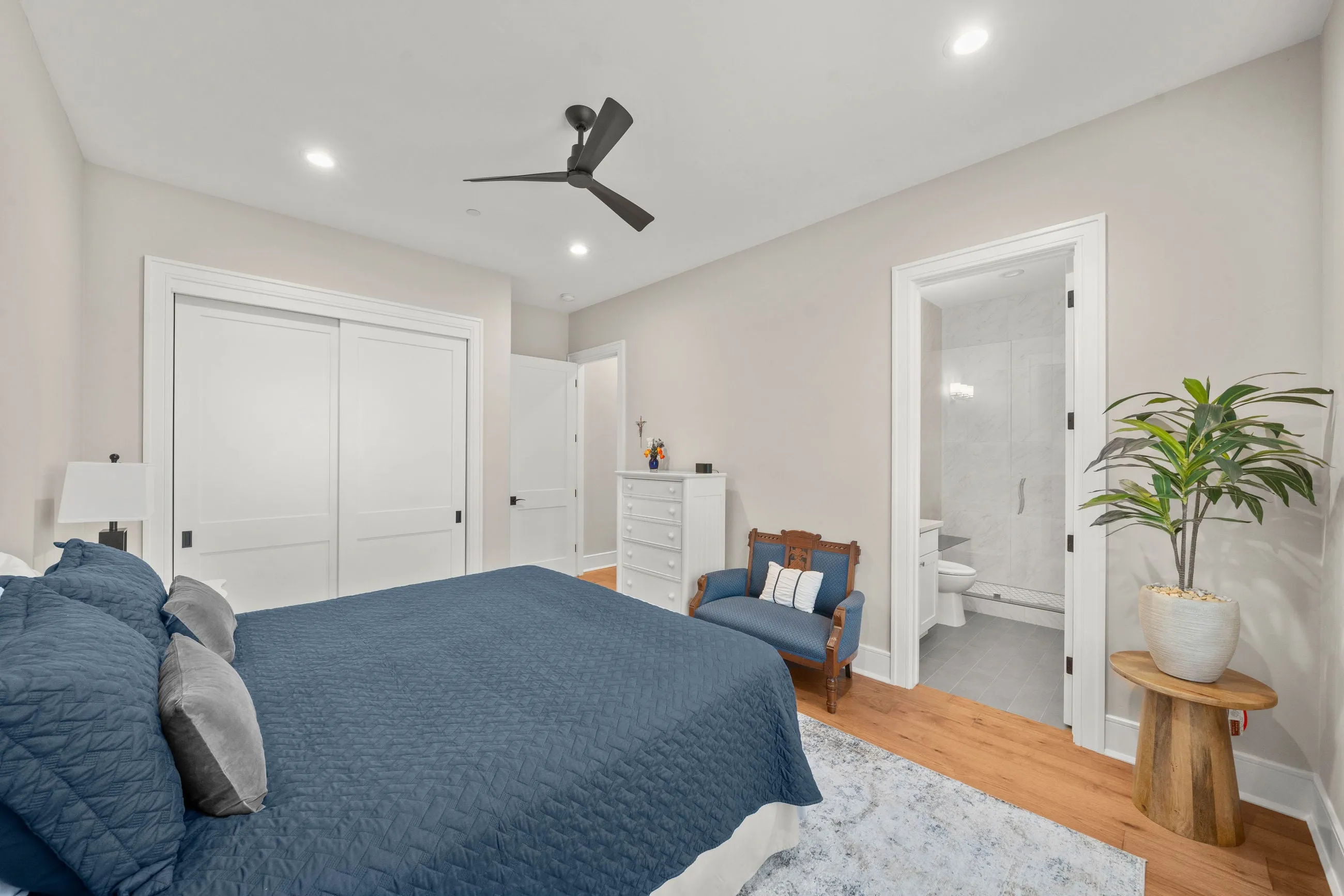 Guest bedroom with navy bedding, double closet doors, and an ensuite walk-in shower