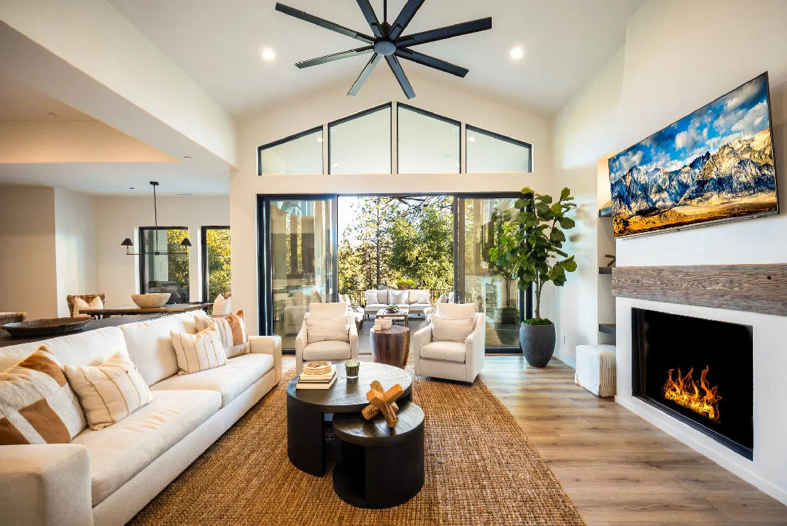 Vaulted great room with linear fireplace, reclaimed-wood mantel, and sliding glass doors to the patio
