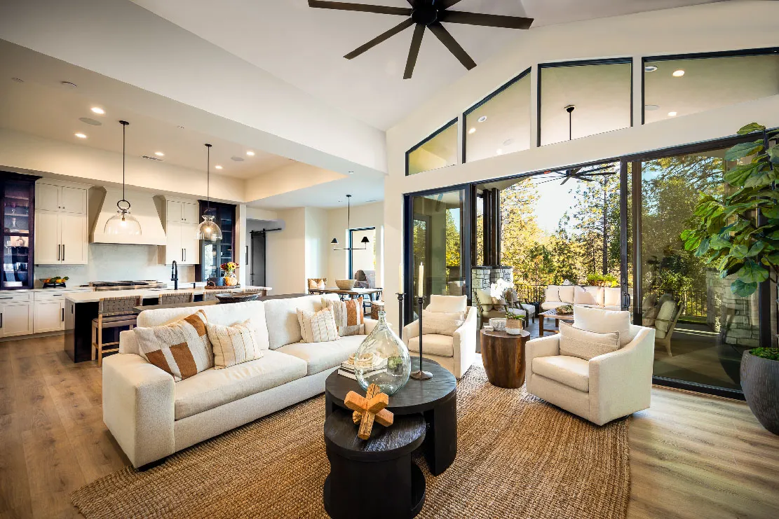 Open great room and kitchen with sliders pulled back to the covered patio and treetop views