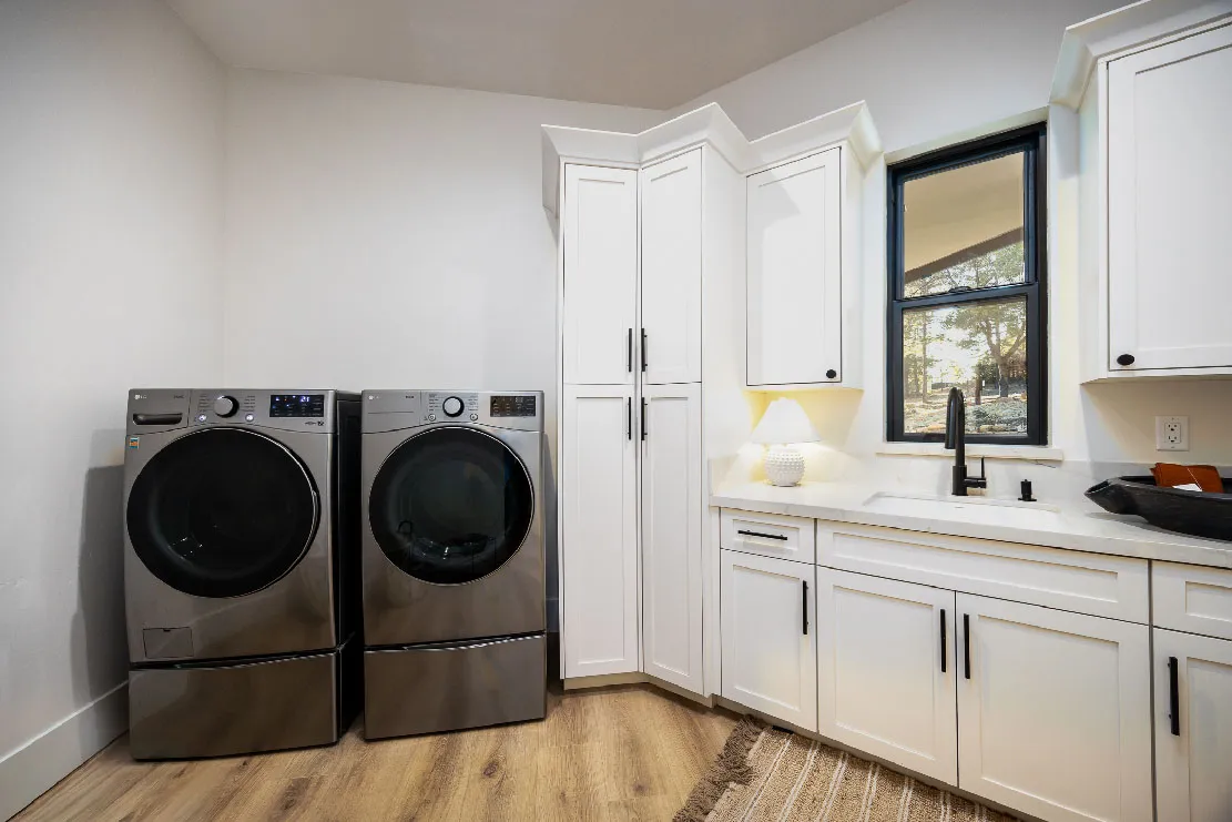 Laundry room with front-load washer and dryer, white shaker cabinetry, and a garden-view window
